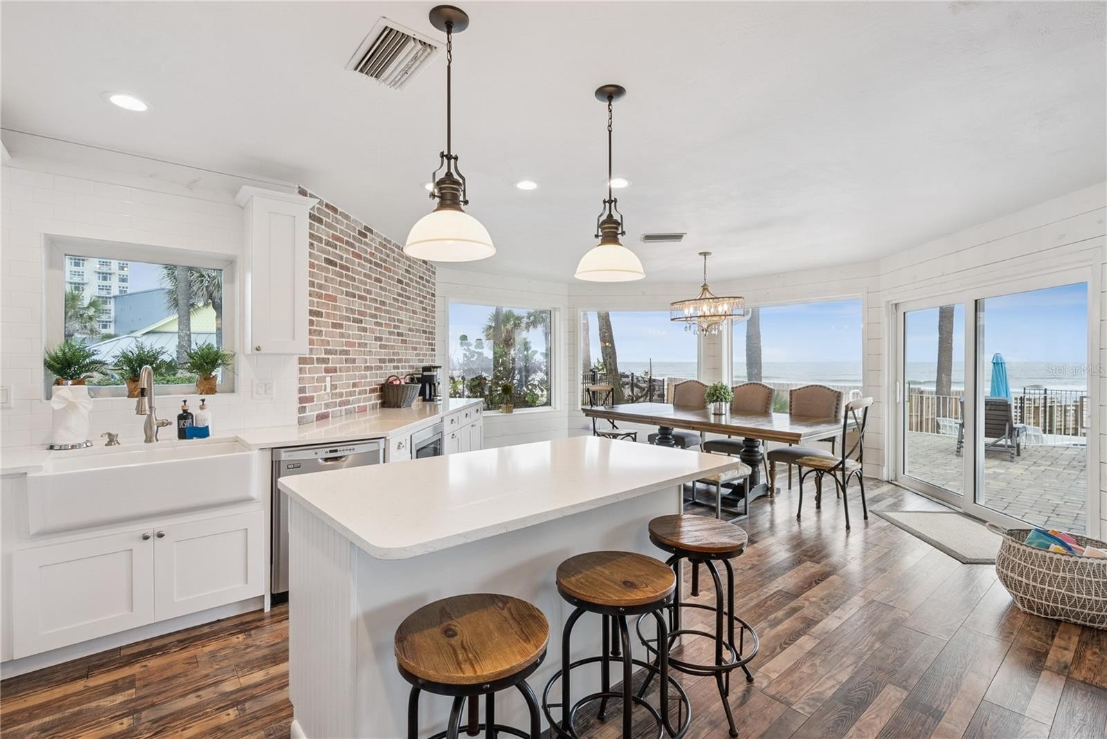 Spacious eat-in kitchen with stainless steel appliances, quartz countertops, breakfast bar seating, and beautiful ocean views—an inviting setting for 