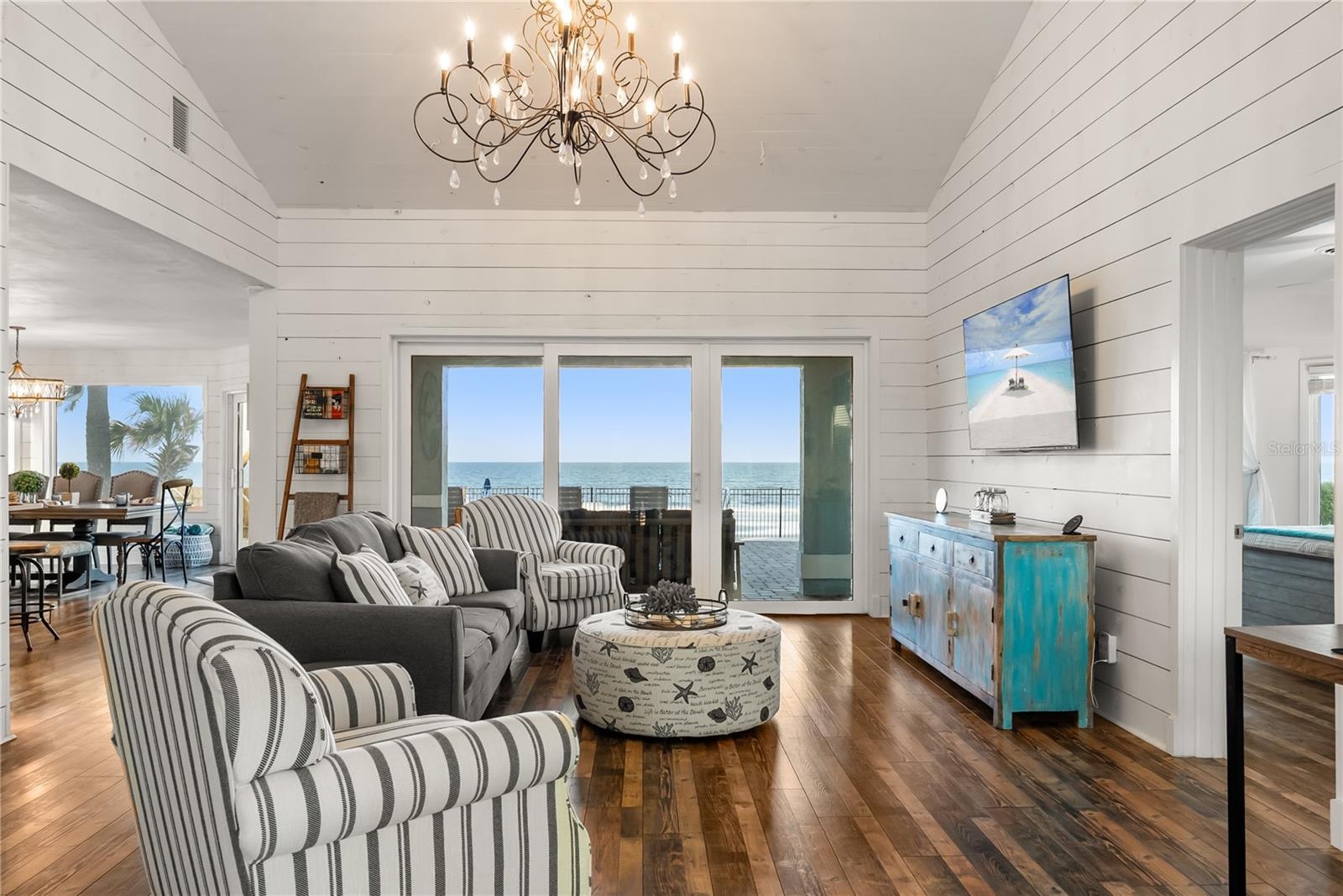 Sweeping Atlantic views take center stage in this bright family room, complemented by coastal furnishings and luxury vinyl plank flooring.