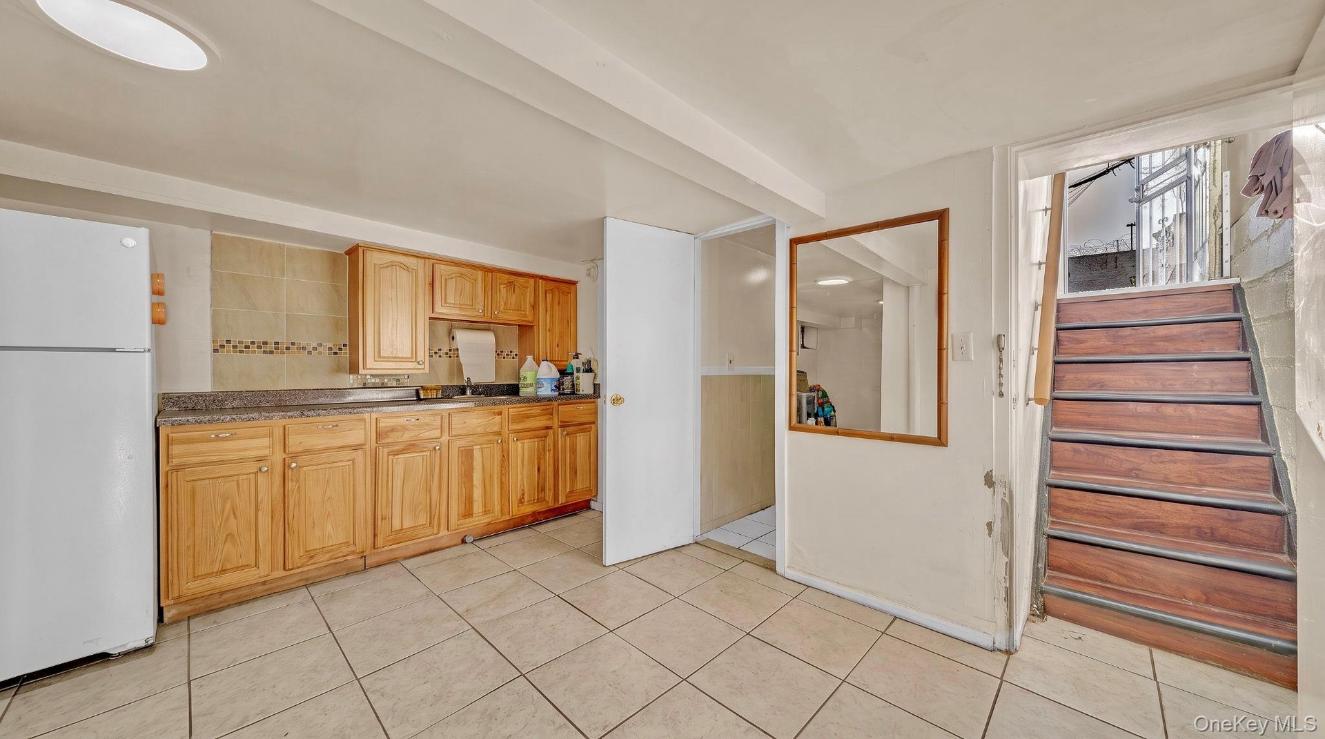 Kitchenette featuring wood cabinetry, stone-look countertops, and tile flooring
