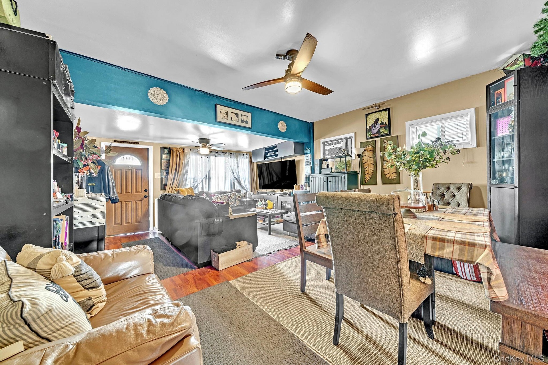 Hardwood flooring, ceiling fan with integrated lighting, and a paneled entry door