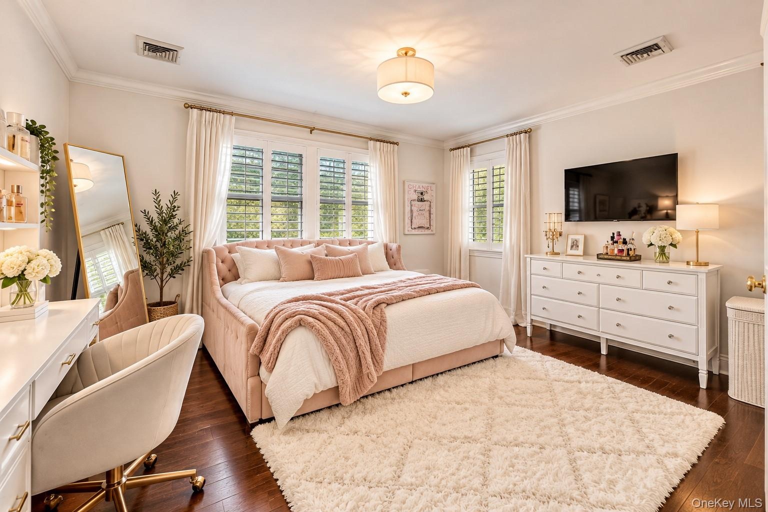 Spacious primary bedroom featuring multiple windows with plantation shutters and natural light, hardwood flooring, an ensuite bathroom, a walk-in clos