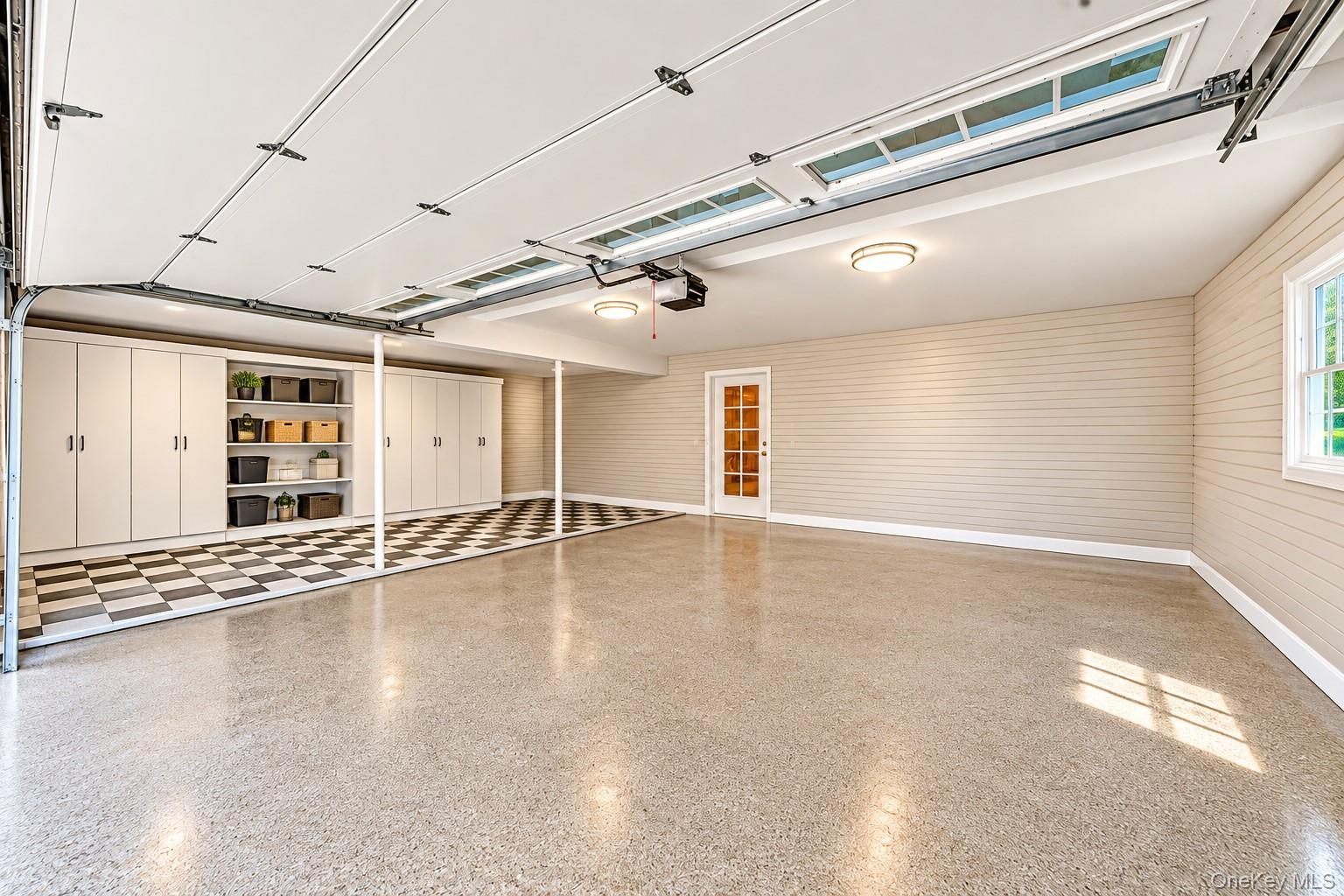 Epoxy-coated flooring, built-in cabinetry with open shelving, checkered flooring, a window, and an interior door with glass panels