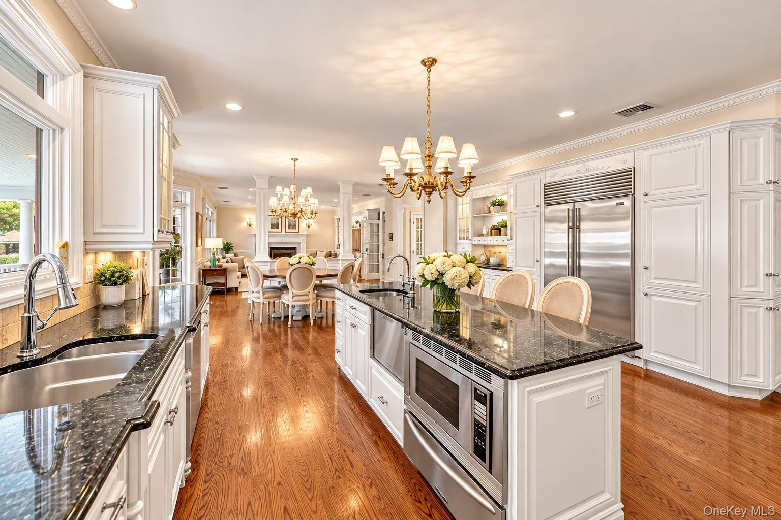 Chef's kitchen featuring white cabinetry with quartz countertops, a large center island with seating, stainless steel appliances including dual ovens 