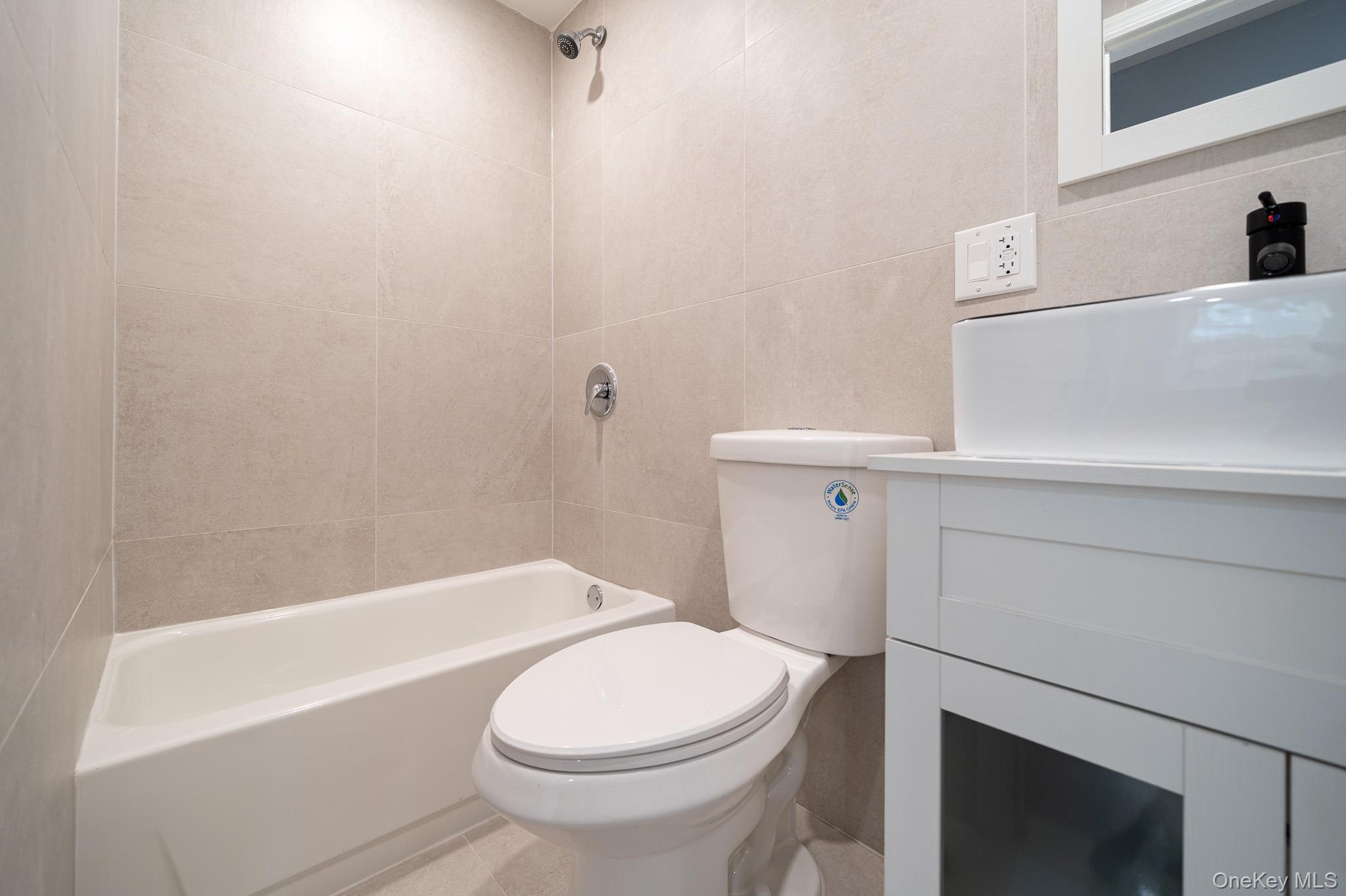 Bathroom with vanity, shower / bathtub combination, and tile walls