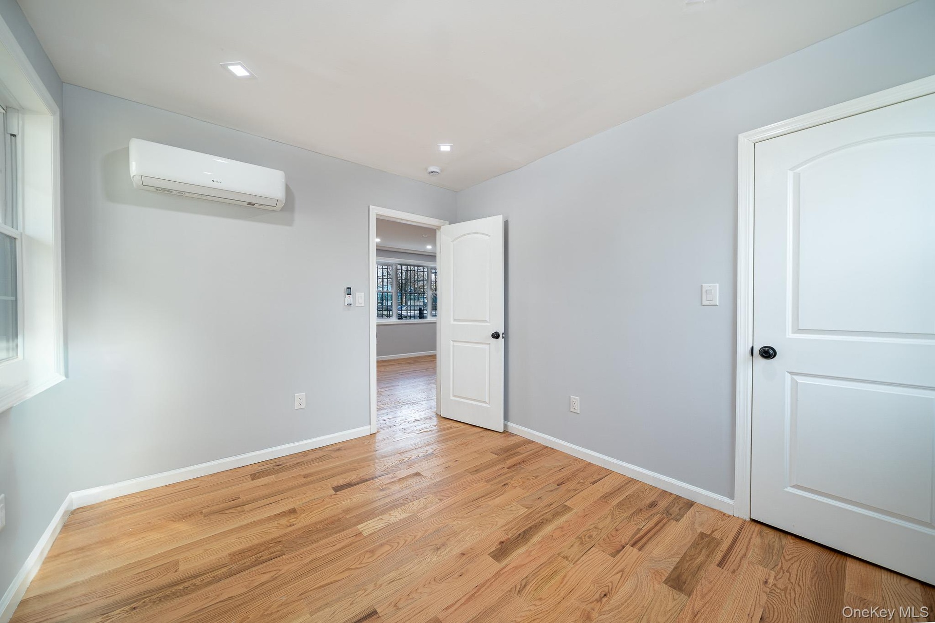 Unfurnished room featuring light wood finished floors and a wall mounted air conditioner