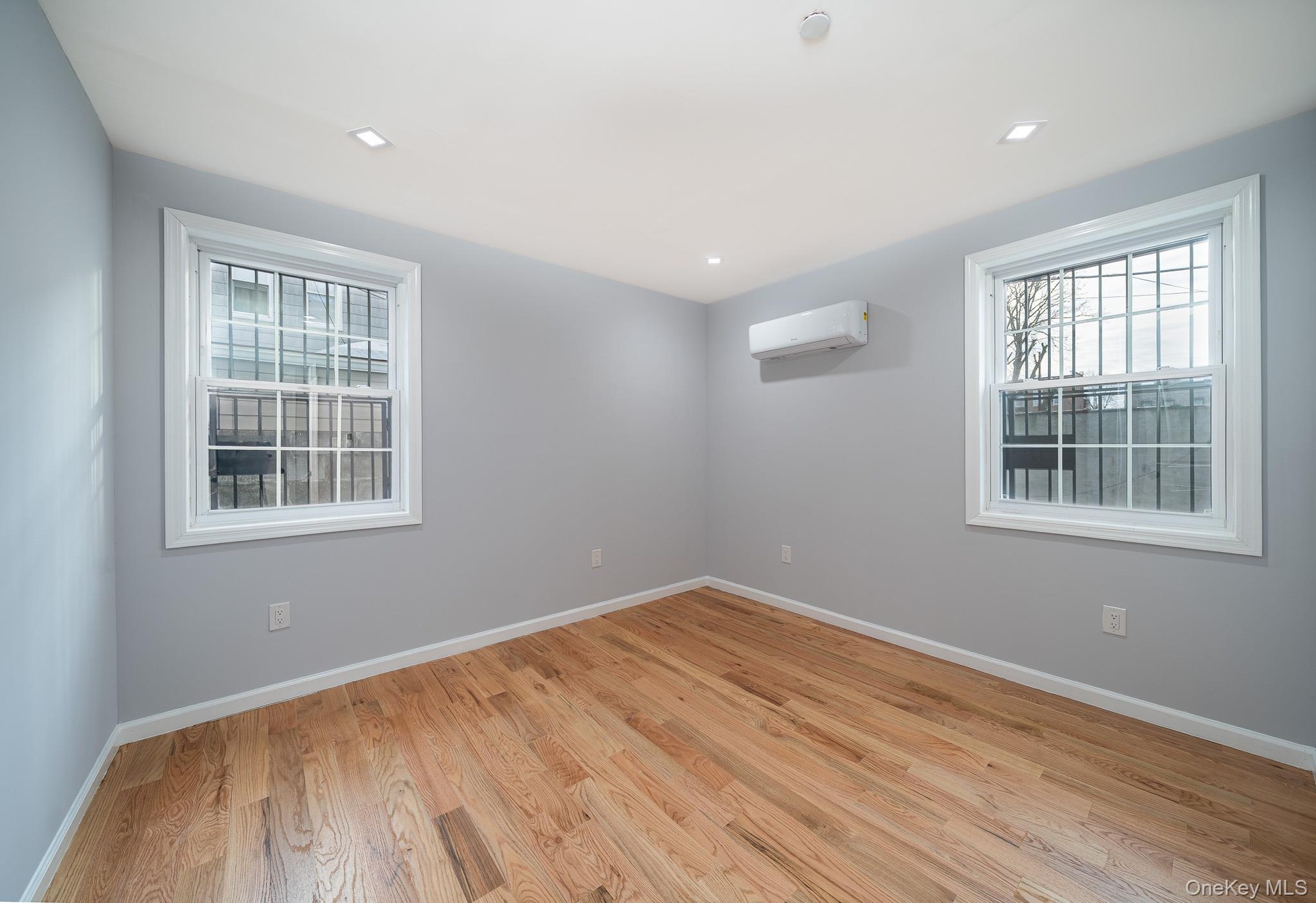Unfurnished room featuring light wood-type flooring, plenty of natural light, and a wall mounted air conditioner