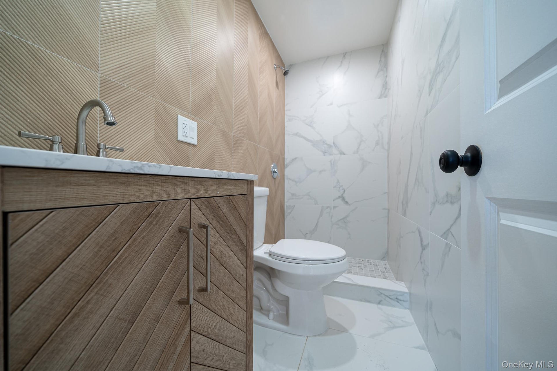 Full bathroom with vanity, tile walls, a marble finish shower, and marble look tiles