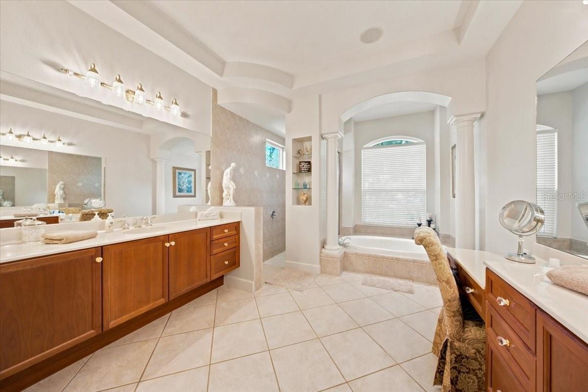 Spacious en-suite bathroom features separate vanities, a soaking tub, and a walk-in shower.