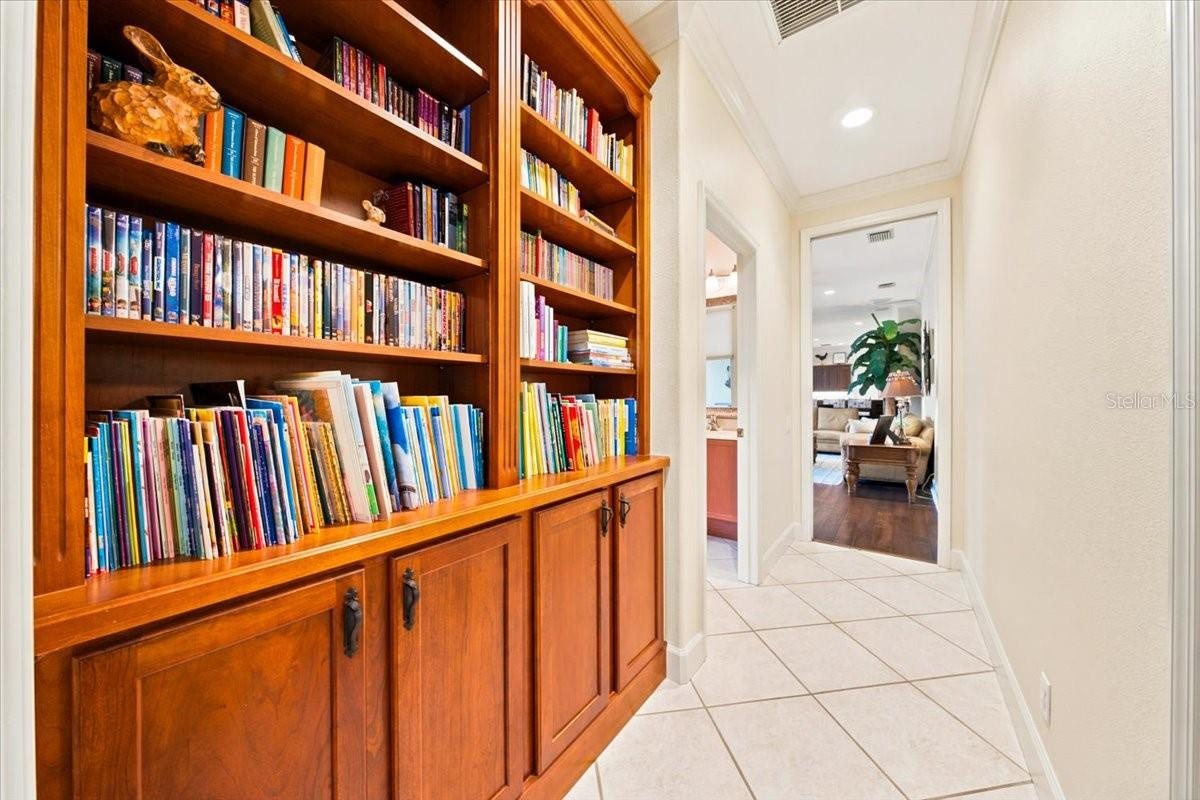 Custom built-in wooden shelving and cabinetry provide extensive display and storage space in the hallway.