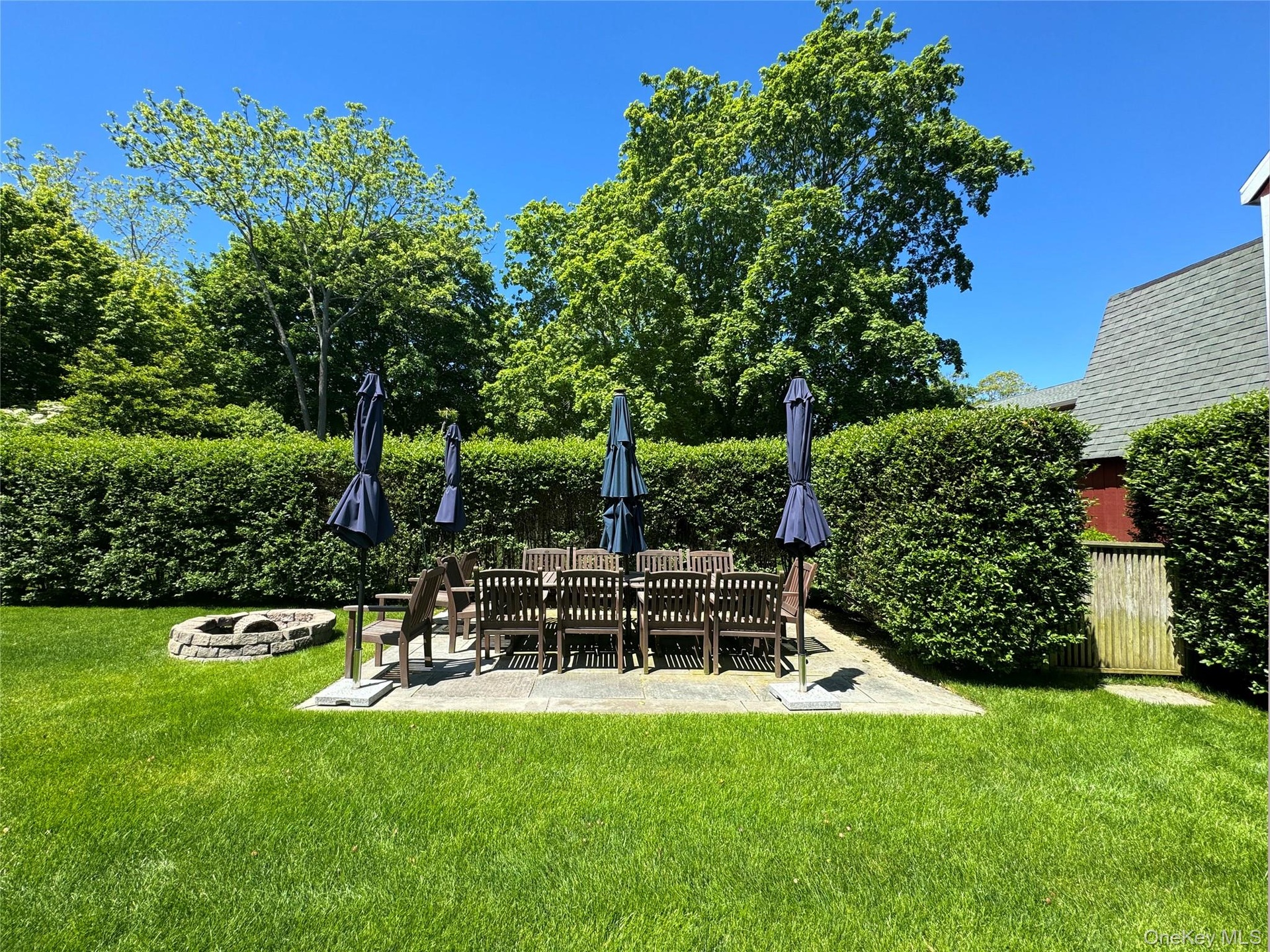 View of grassy yard featuring a fire pit and a patio