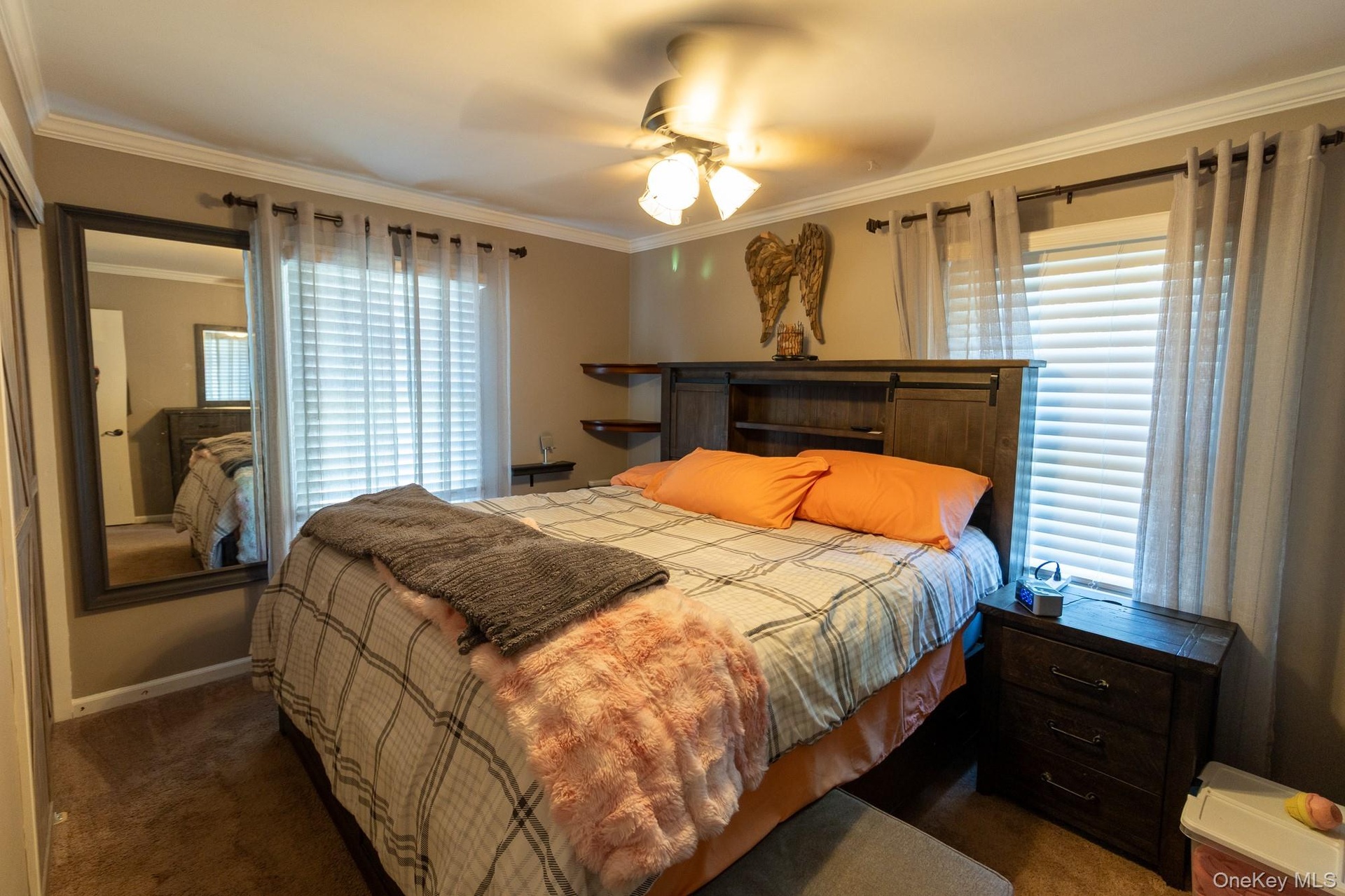 The primary bedroom features natural light from multiple windows and a ceiling fan.