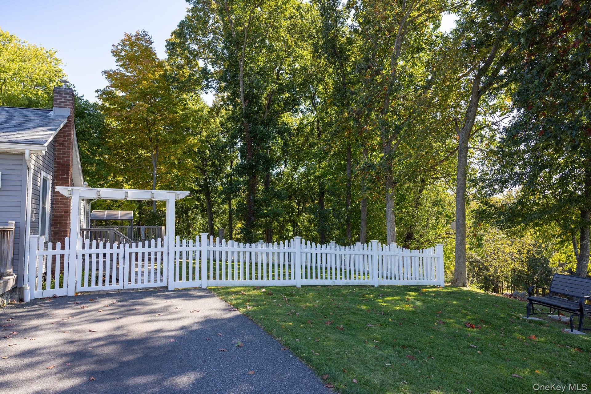 View of the open lawn bordered by fencing and mature trees.