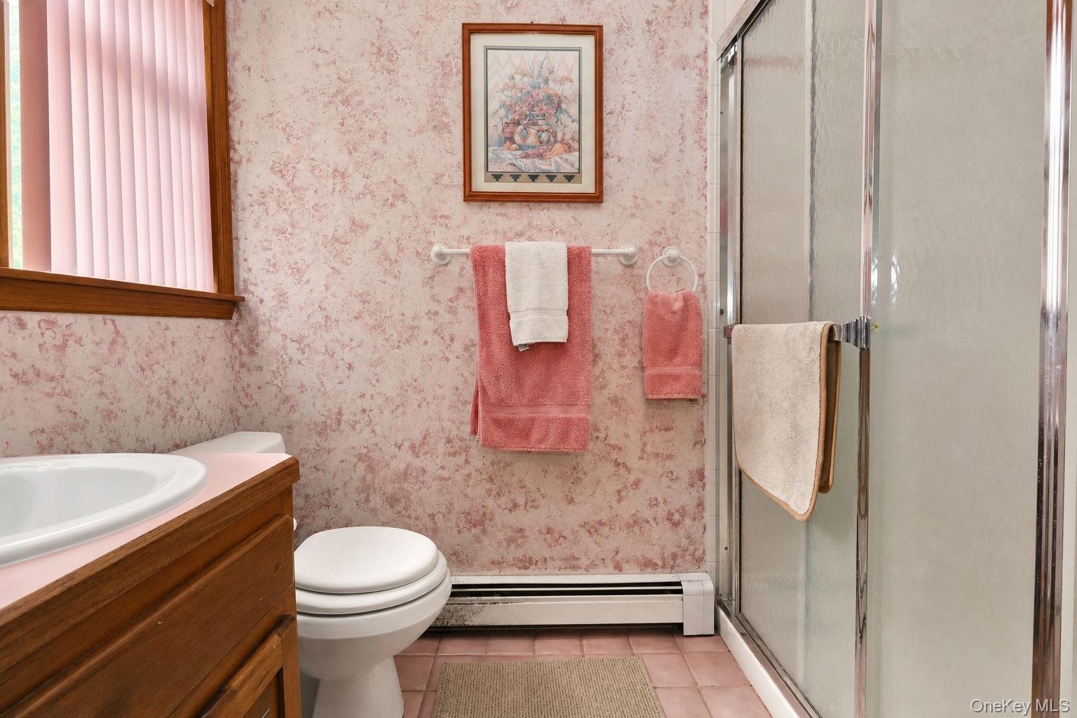 Bathroom featuring wood-finish vanity, integrated sink, and glass door walk in shower enclosure