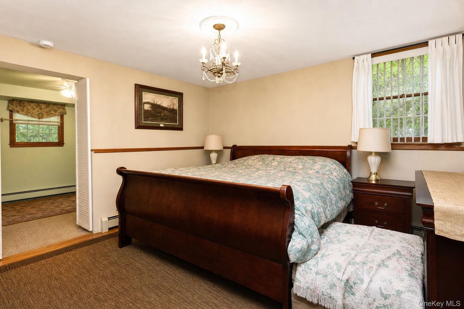 Carpeted flooring, chandelier lighting, wood trim, and a window with blinds