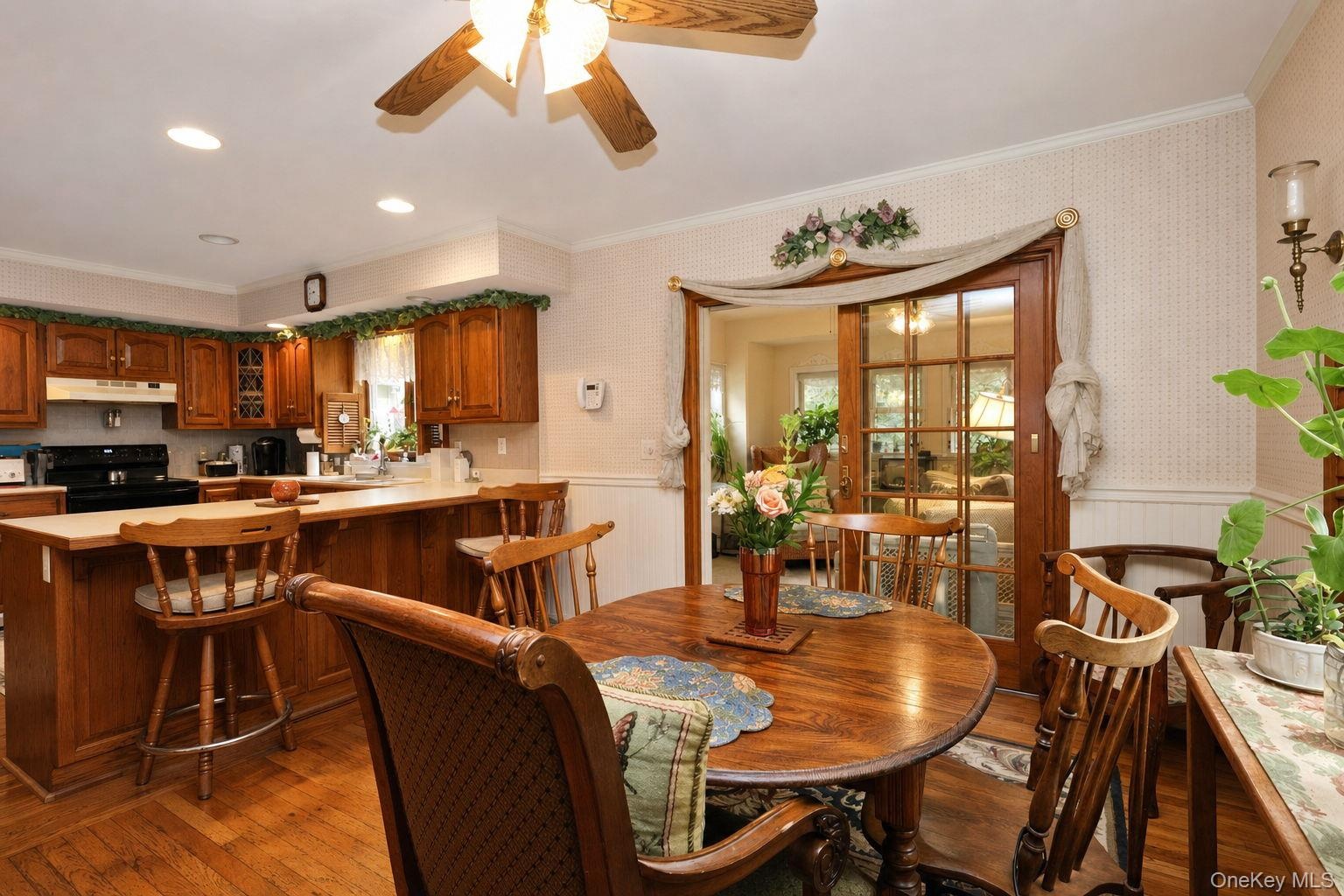 Wood-finish flooring, wood cabinetry, built-in ceiling lighting, and a ceiling fan Peninsula with storage and entrance to the bonus room