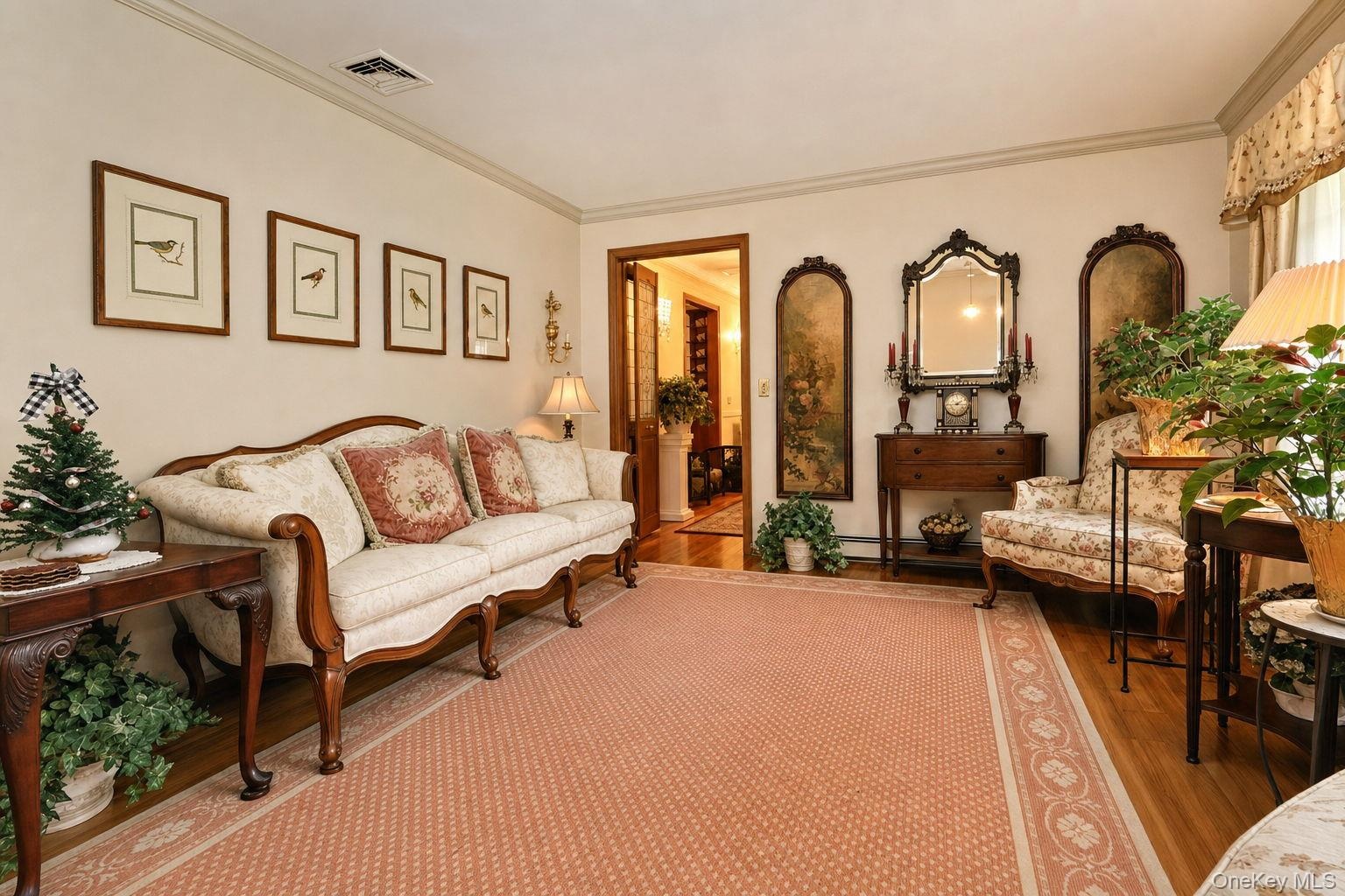 Hardwood flooring, crown molding, and a decorative area rug define this inviting space