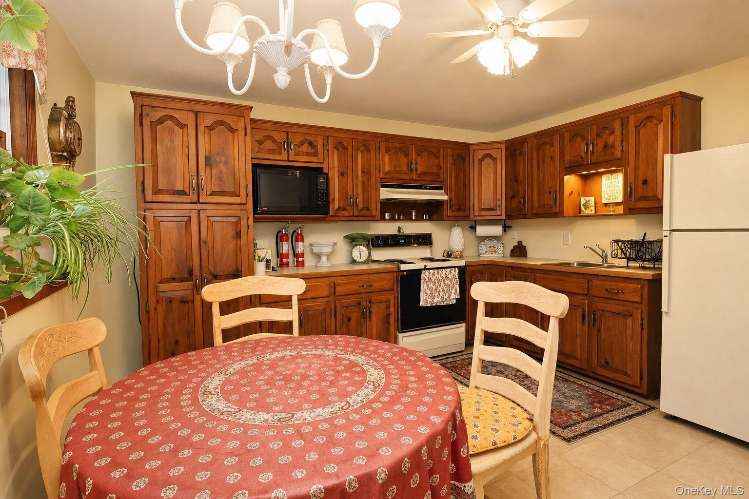 Kitchen featuring wood-finish cabinetry, built-in microwave, and ceiling fan