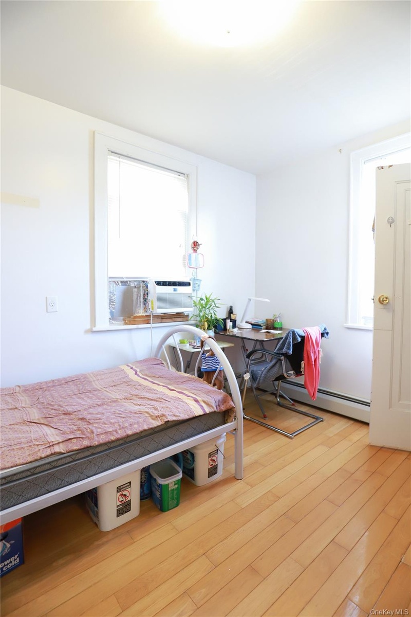 Hardwood flooring, painted white walls, white trim, and a window with a window-mounted air conditioning unit