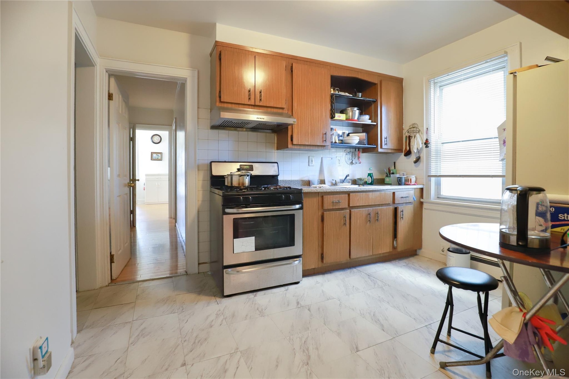 Bright, open kitchen featuring wood-finish cabinetry, stainless steel appliances including a gas range, white countertops, and abundant natural light 