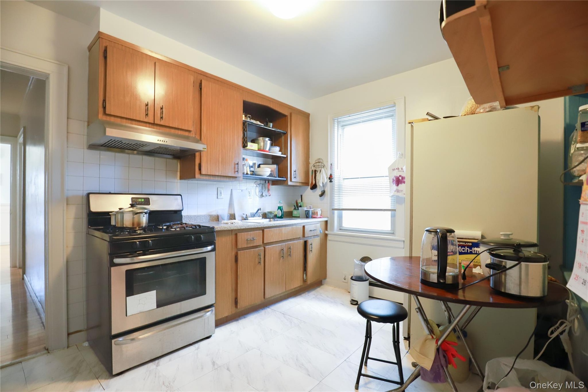 Kitchen featuring wood-finish cabinetry, stainless steel gas range, and white tiled backsplash