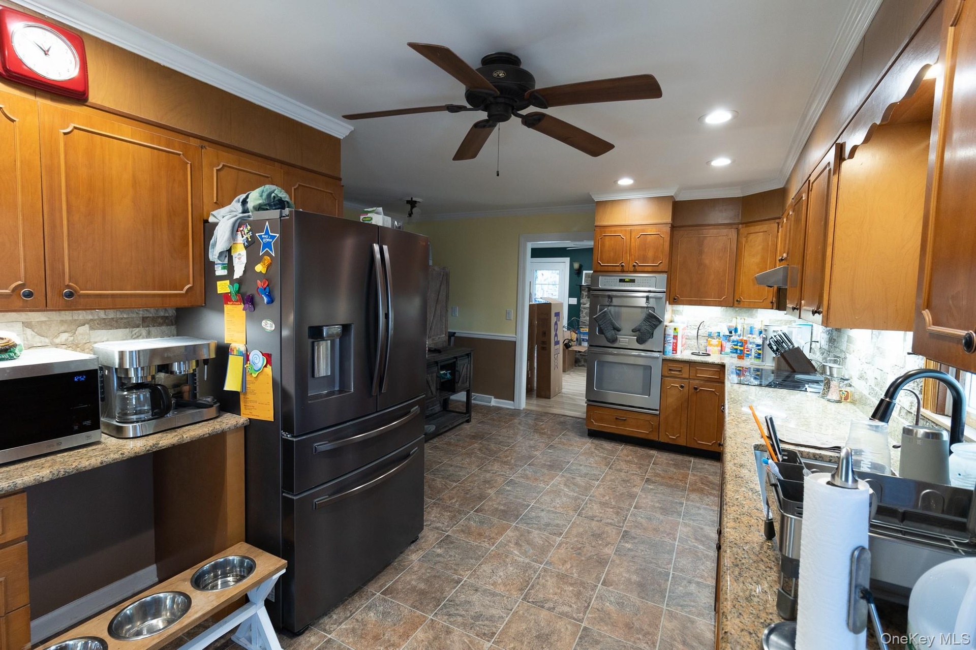 The kitchen features wood cabinetry, vast countertop workspace and a ceiling fan for comfort.