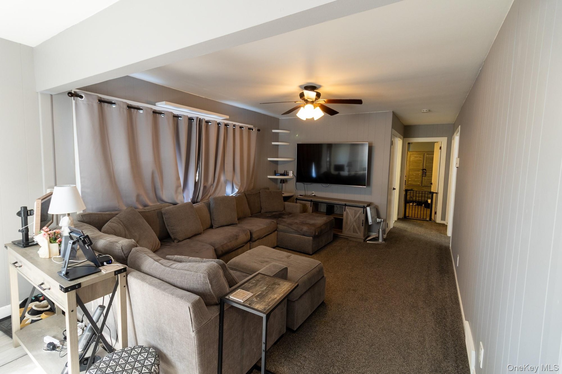 Comfortable living area featuring a ceiling fan, multiple windows and natural light