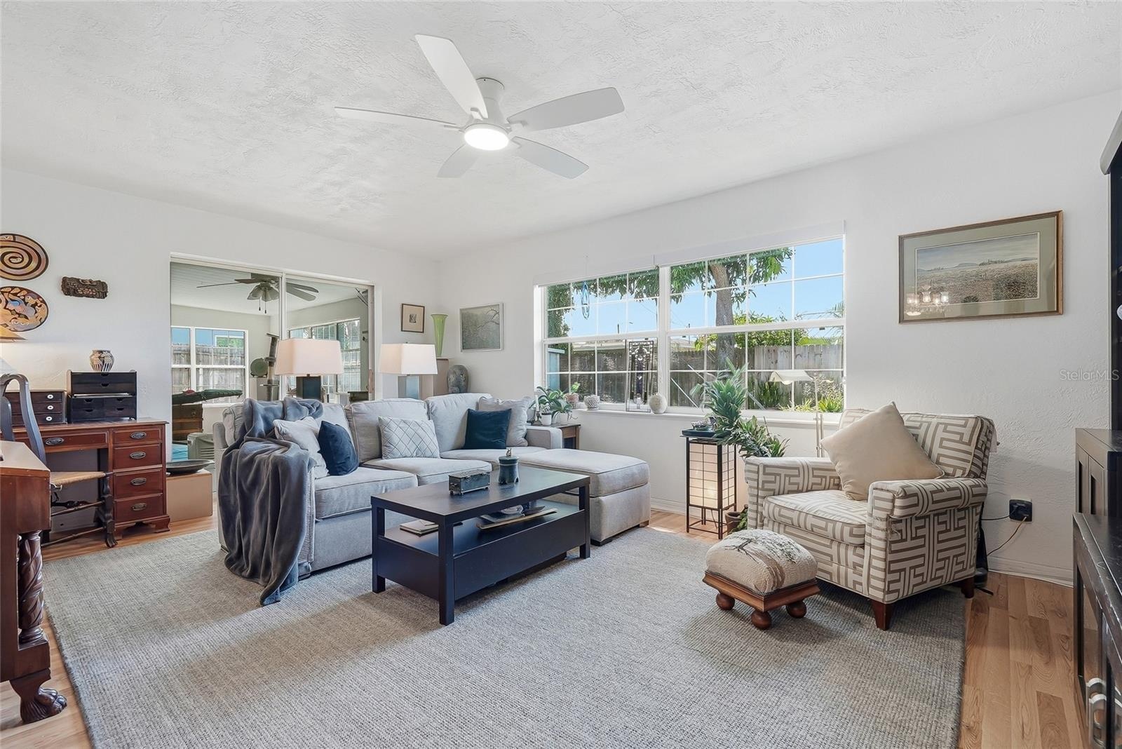 Sunlight pours through a wide window in the family room, while sliding glass doors connect this comfortable gathering space to the enclosed Florida ro