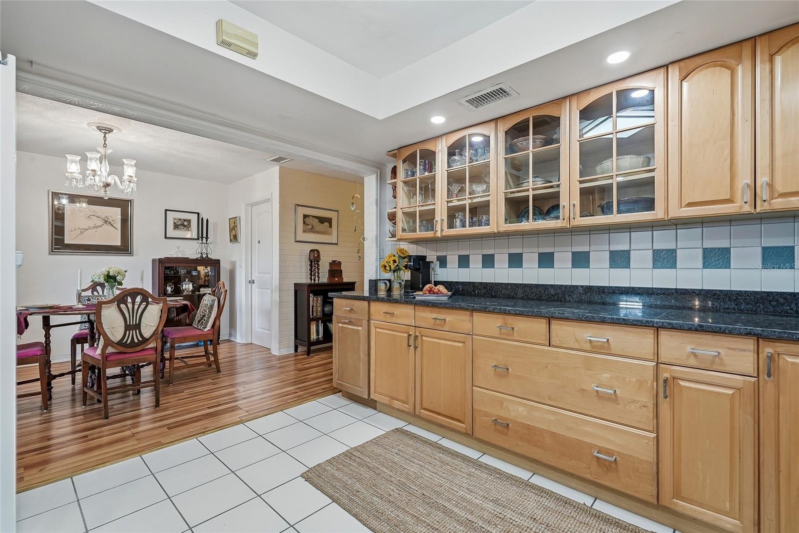 Glass-front cabinetry adds charm above an expansive counter, perfect for meal preparation or serving a spread just steps from the dining table.