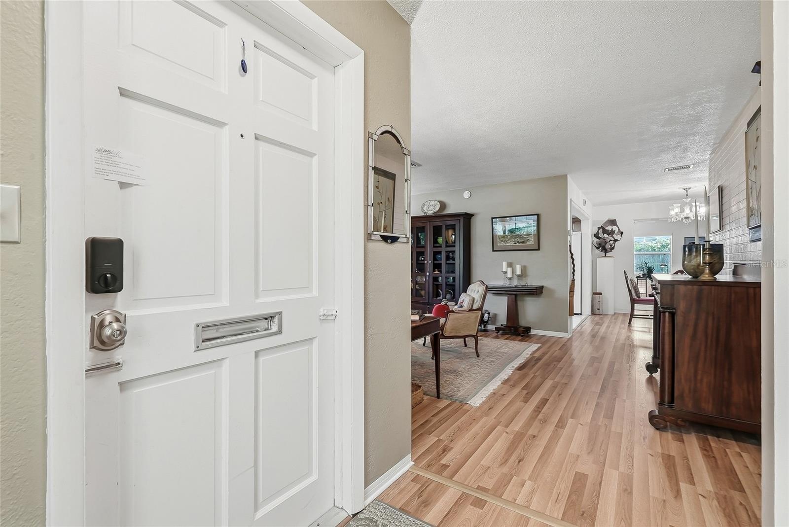 An inviting entry opens to comfortable living spaces, with warm wood flooring connecting the living and dining areas.