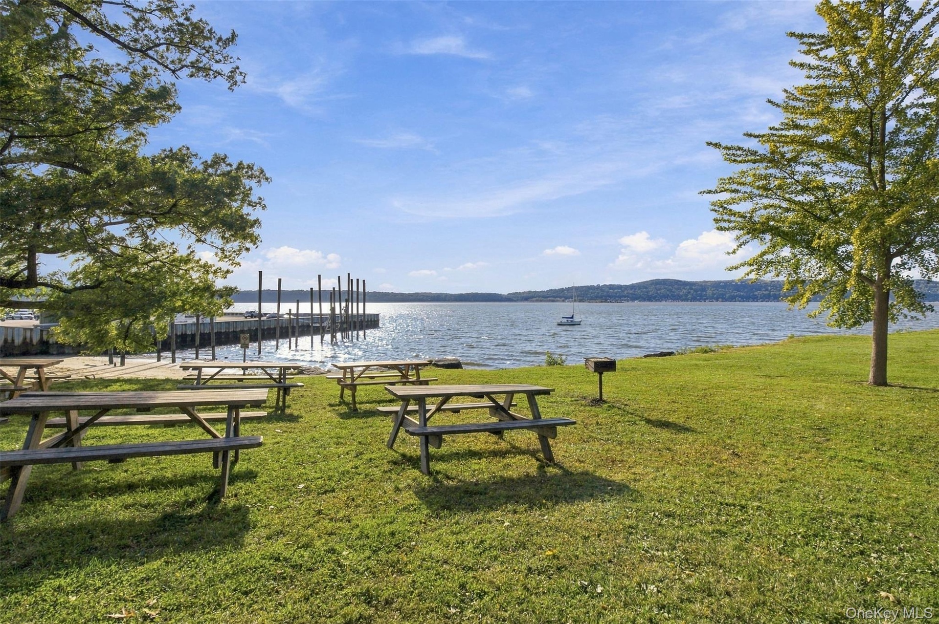 Waterfront property featuring a substantial dock, expansive grassy areas, and mature trees