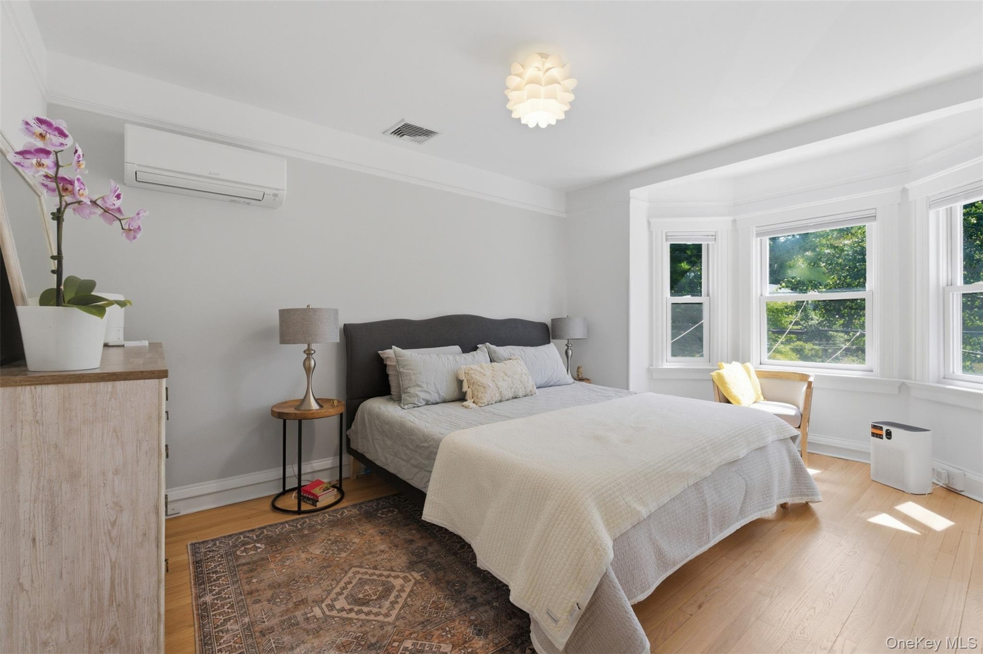 Hardwood flooring, bay windows, crown molding, white ceiling fan, and wall-mounted air conditioning unit