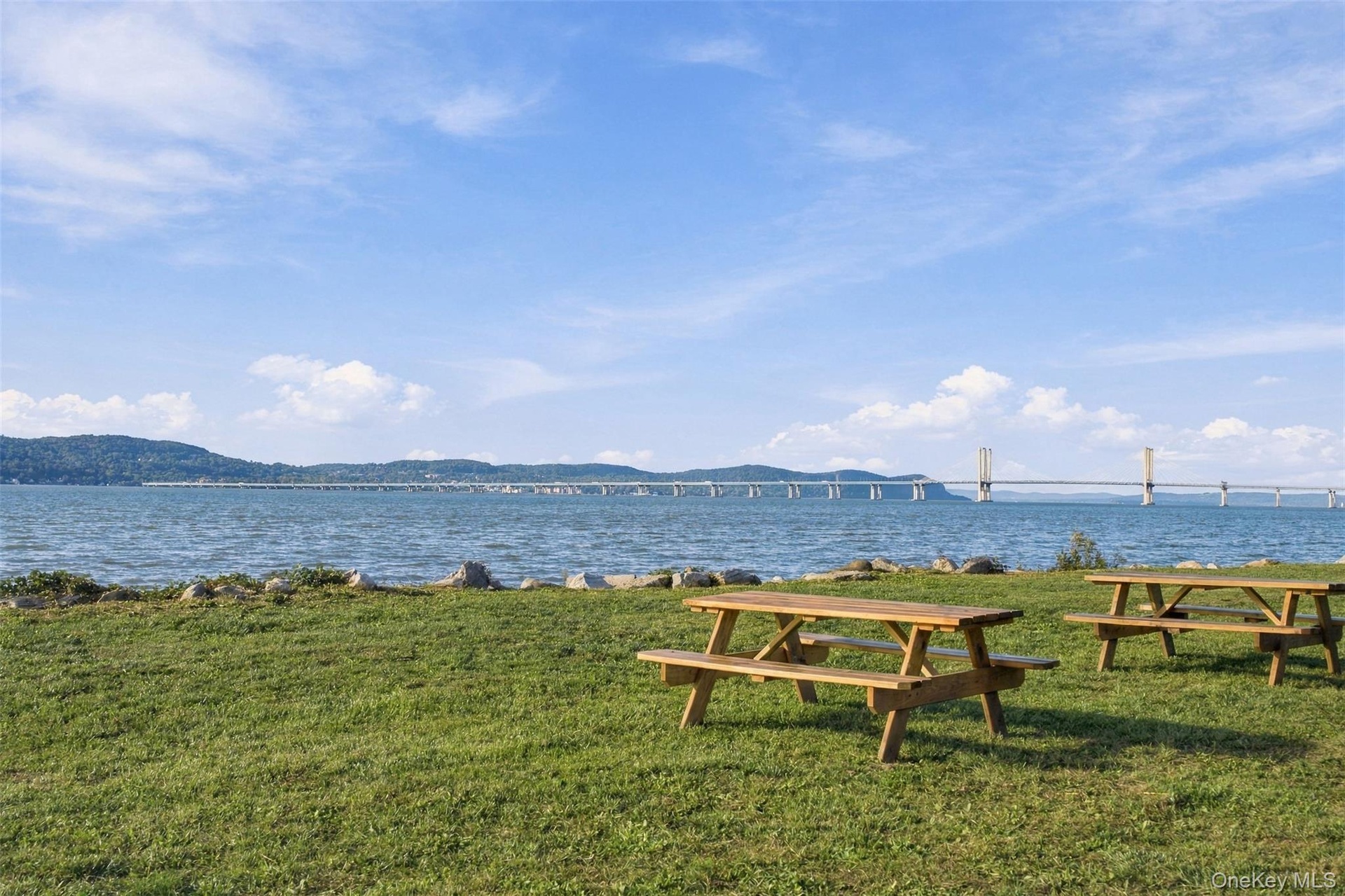 Waterfront property with expansive green space, featuring a long-span bridge in the background