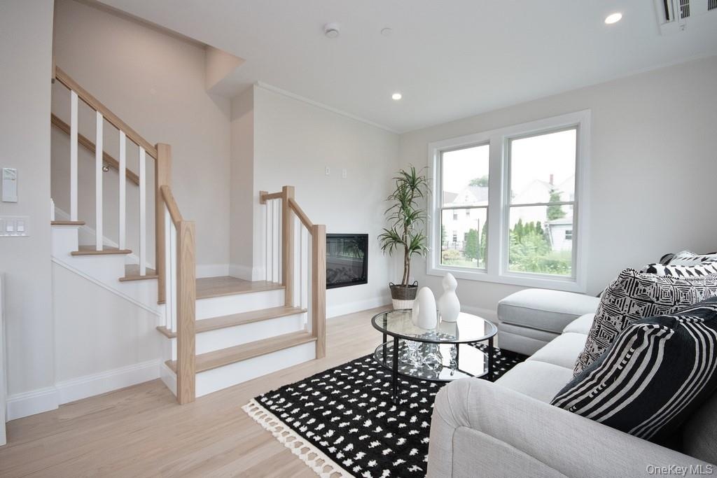 Living room featuring recessed lighting, fireplace, and stairs leading to second floor.