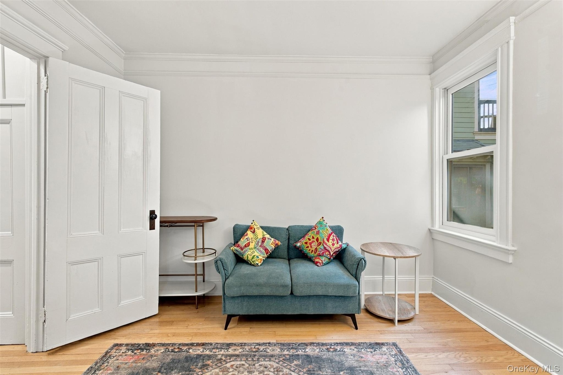 Hardwood flooring, crown molding, white interior door, white window trim, and white baseboards