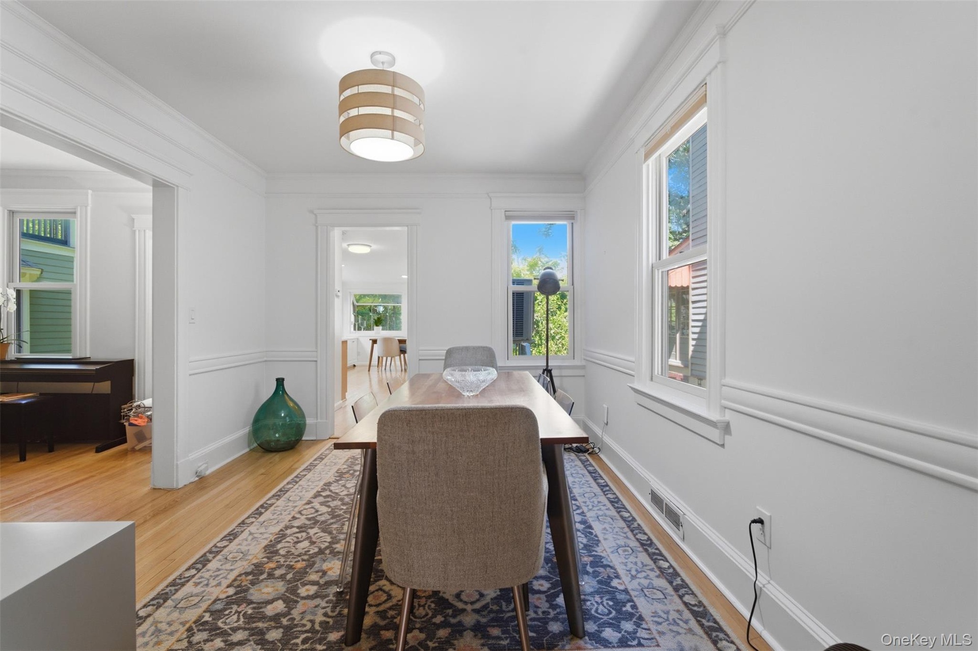 Hardwood flooring, white painted walls, decorative chair rail, recessed windows with white trim, and a contemporary ceiling fixture