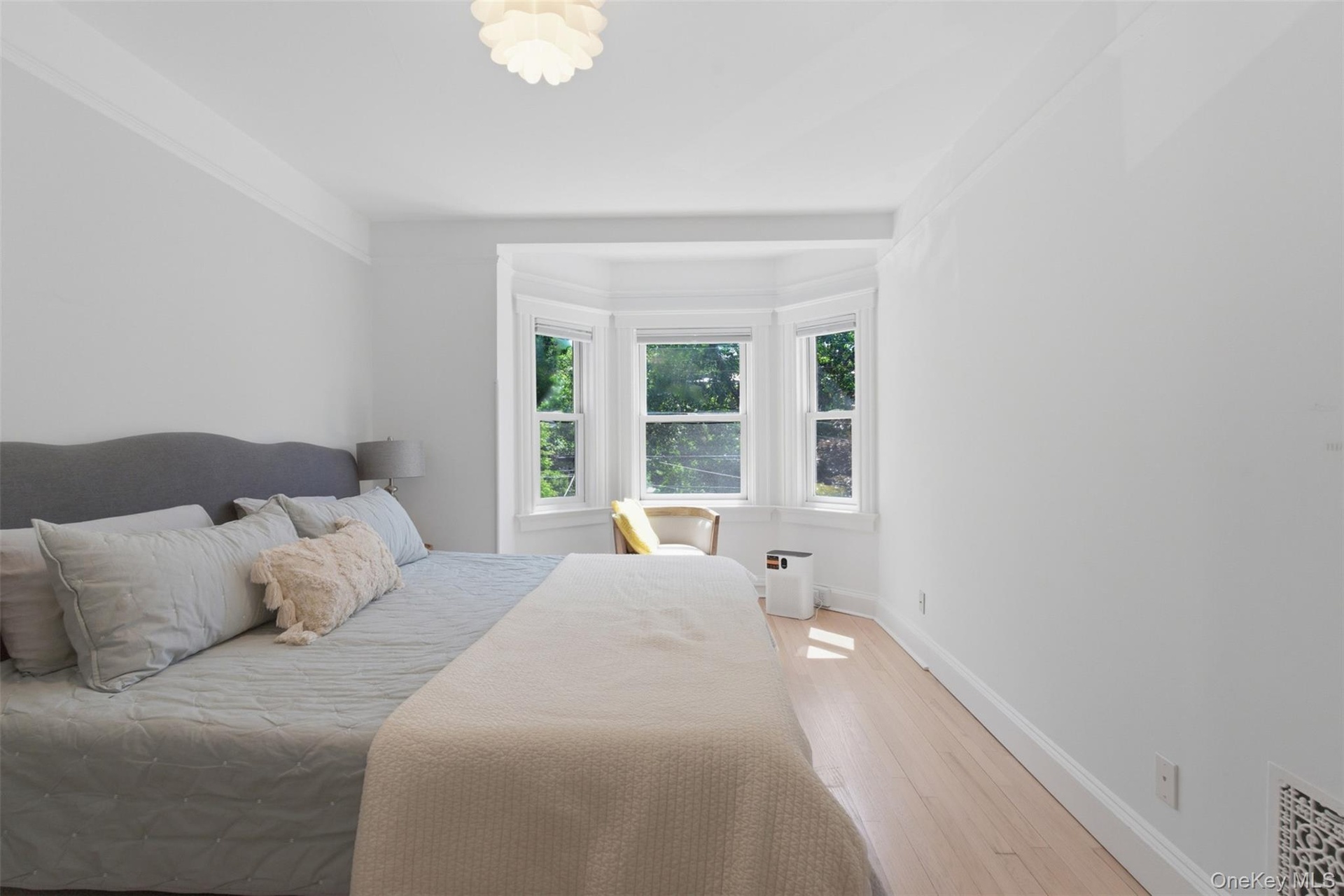 Hardwood-style flooring with white baseboards, a bay window with multiple panes, and a modern ceiling fixture