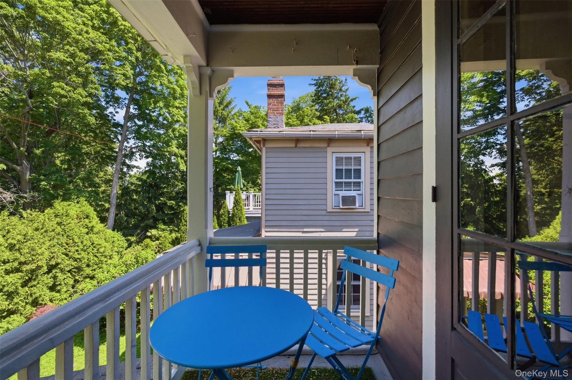Covered balcony featuring white spindle railings, dark wood-finish ceiling, and shingle siding