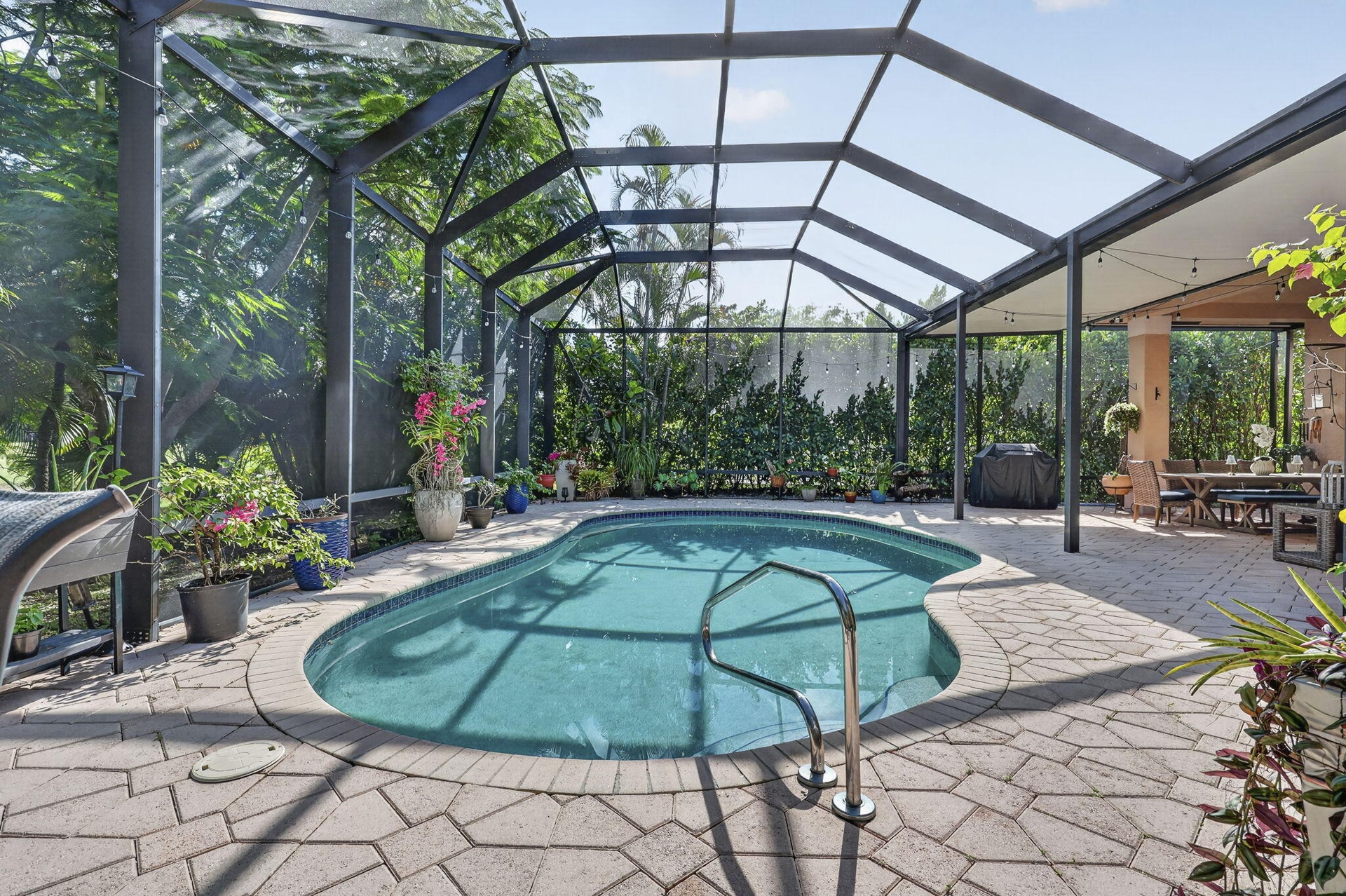 Screened enclosure with a freeform swimming pool, paver deck, and covered patio area