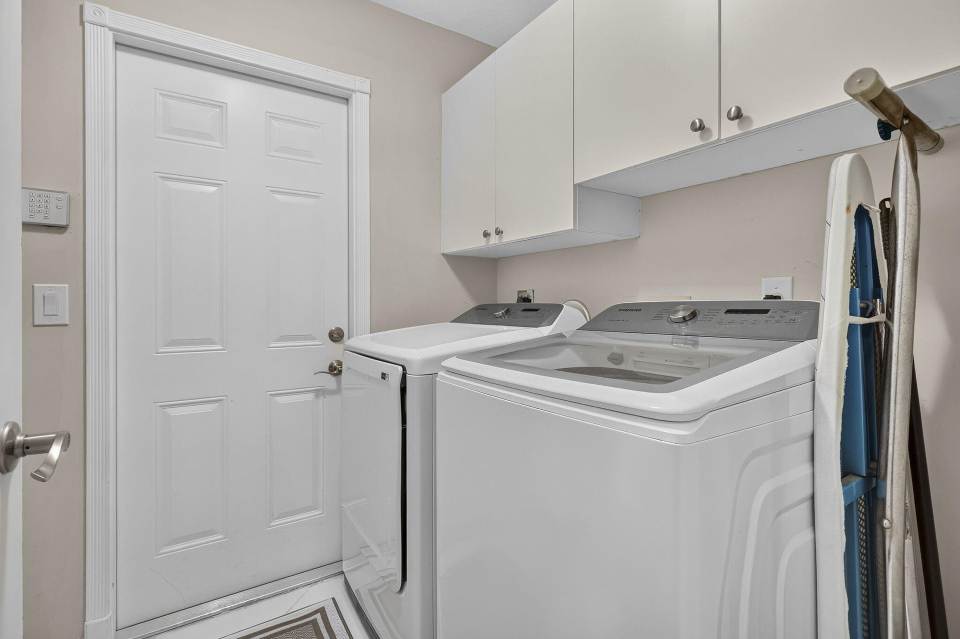 Laundry area with white cabinetry and patterned floor tile