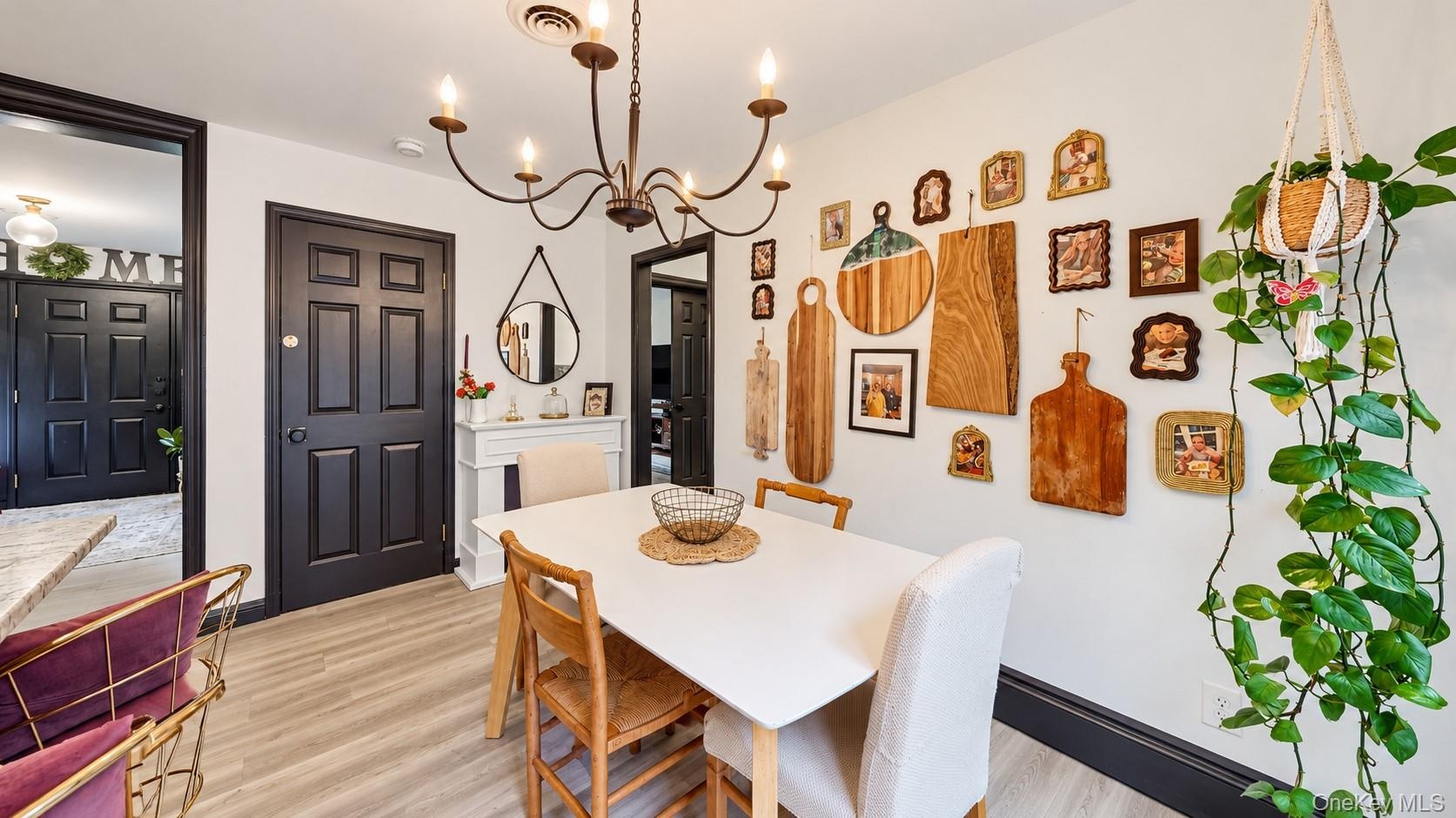 Light wood-finish flooring, dark trim accents, and a bronze chandelier with candelabra bulbs