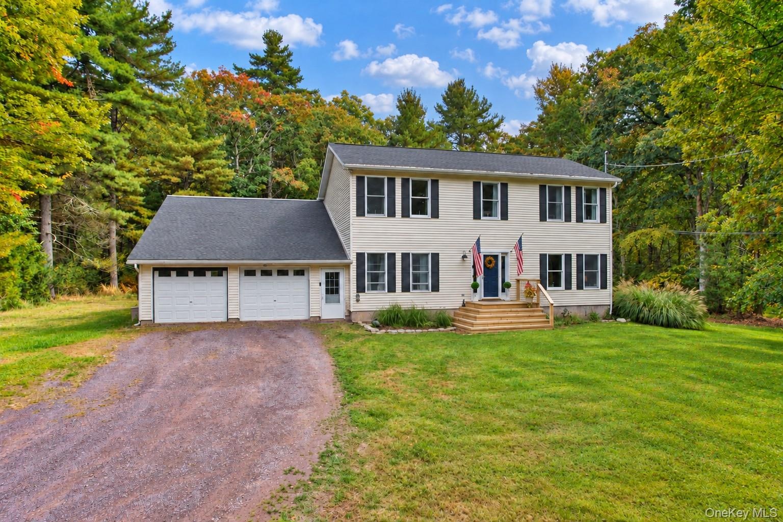 Two-story residence with a two-car garage, gravel driveway, and a welcoming front porch with wooden steps