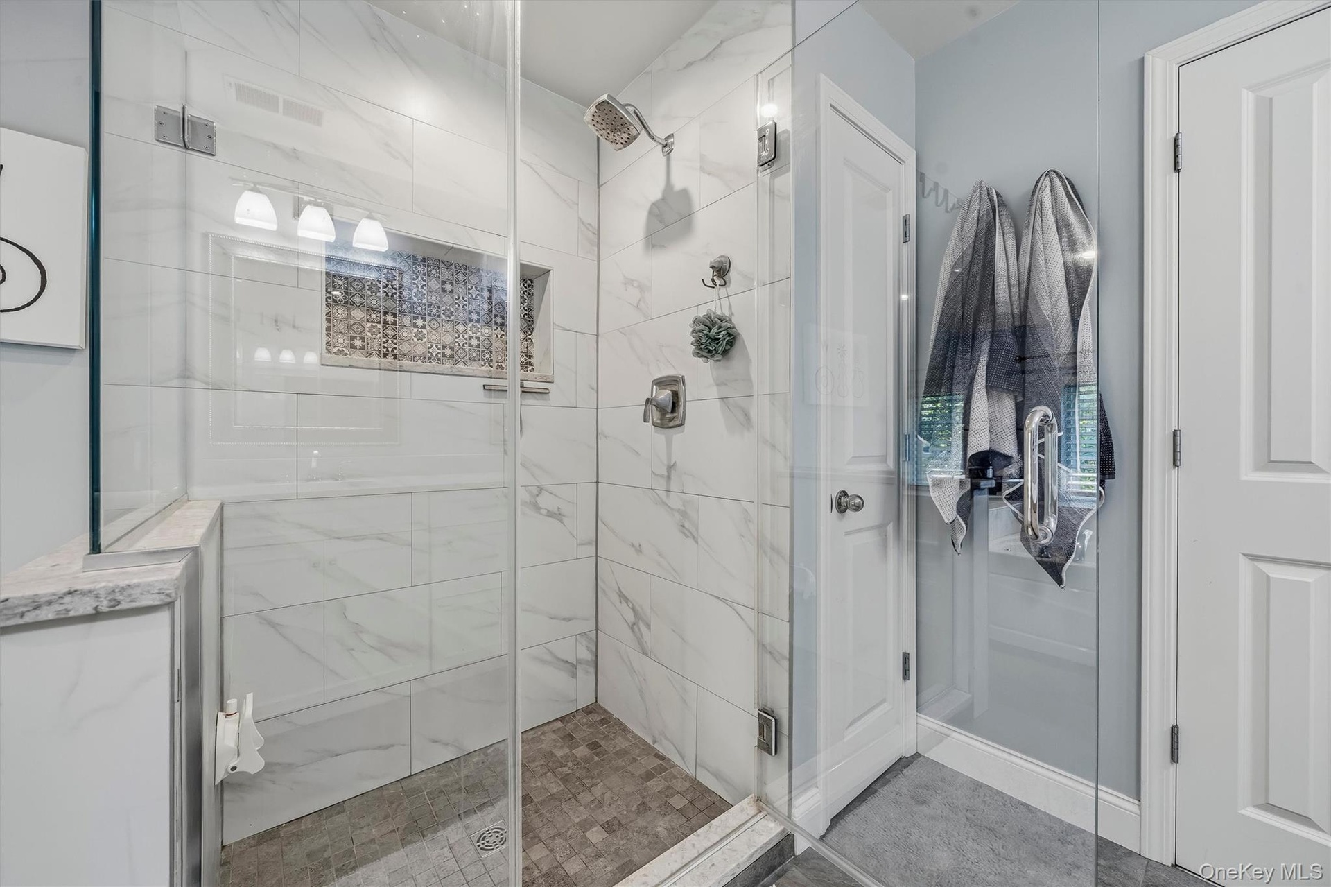 A seamless glass shower and a linen closet.