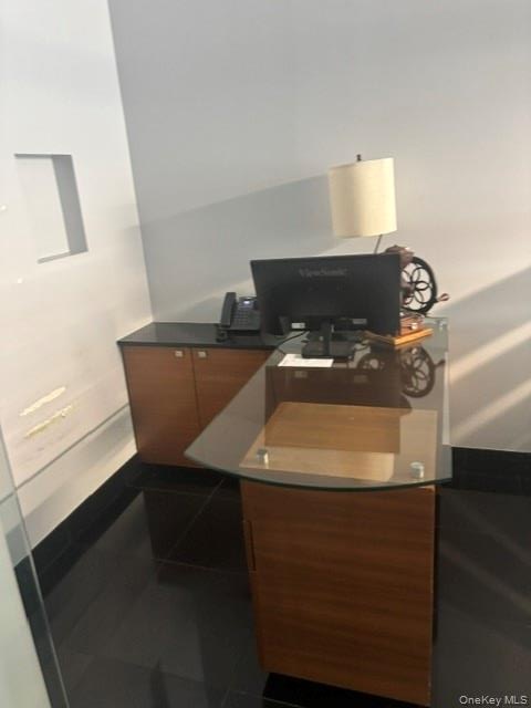 Built-in desk with a curved glass top, wood-finish cabinetry, and a black countertop