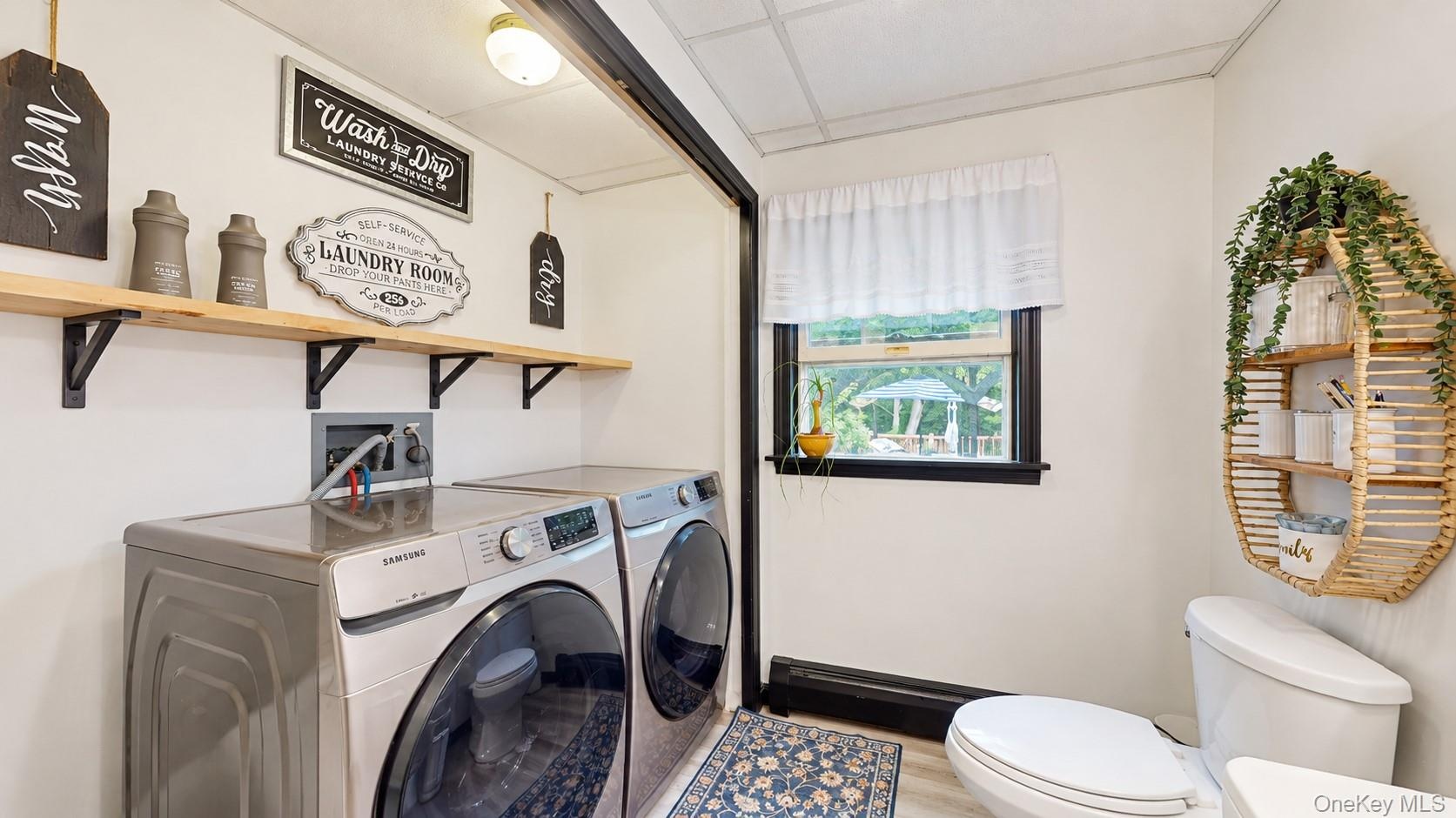 Laundry area featuring upper shelving, a window, and wood-finish flooring