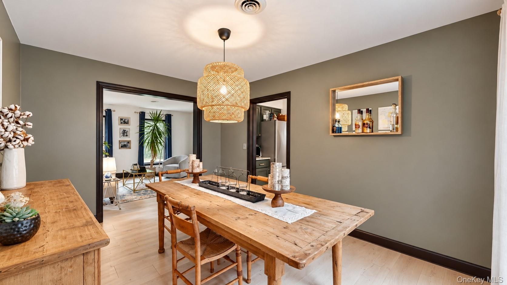 Hardwood-style flooring, woven pendant lighting, dark trim, and a framed wall mirror