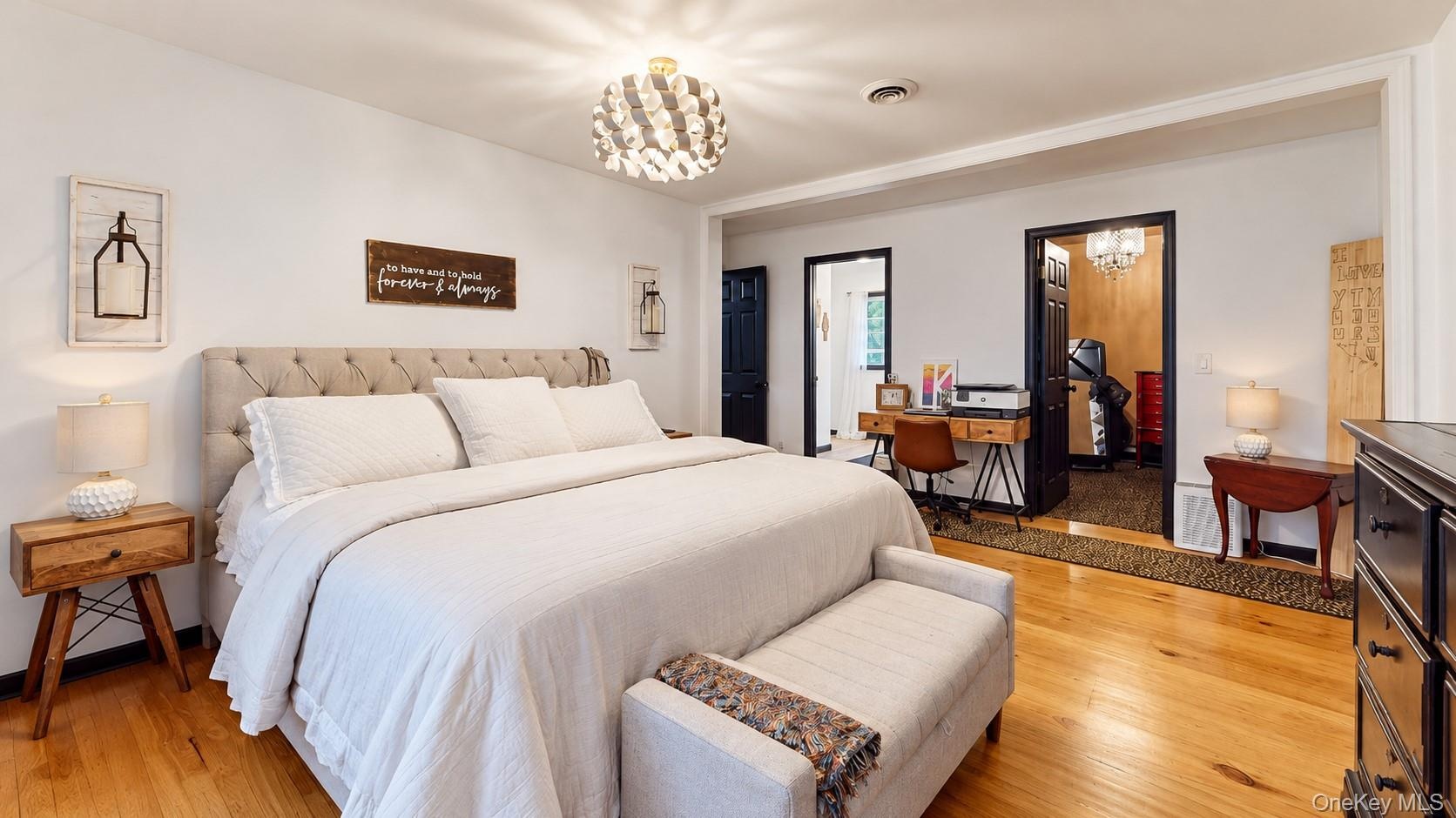 Hardwood flooring, tufted headboard, recessed lighting, ceiling-mounted light fixture, multiple doorways