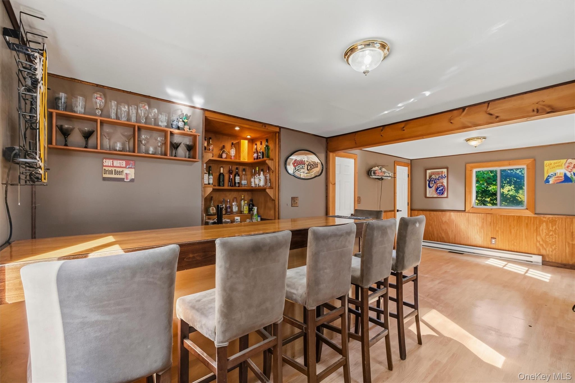 Wood-finish flooring with a built-in bar, wood paneling, and an integrated corner shelving unit
