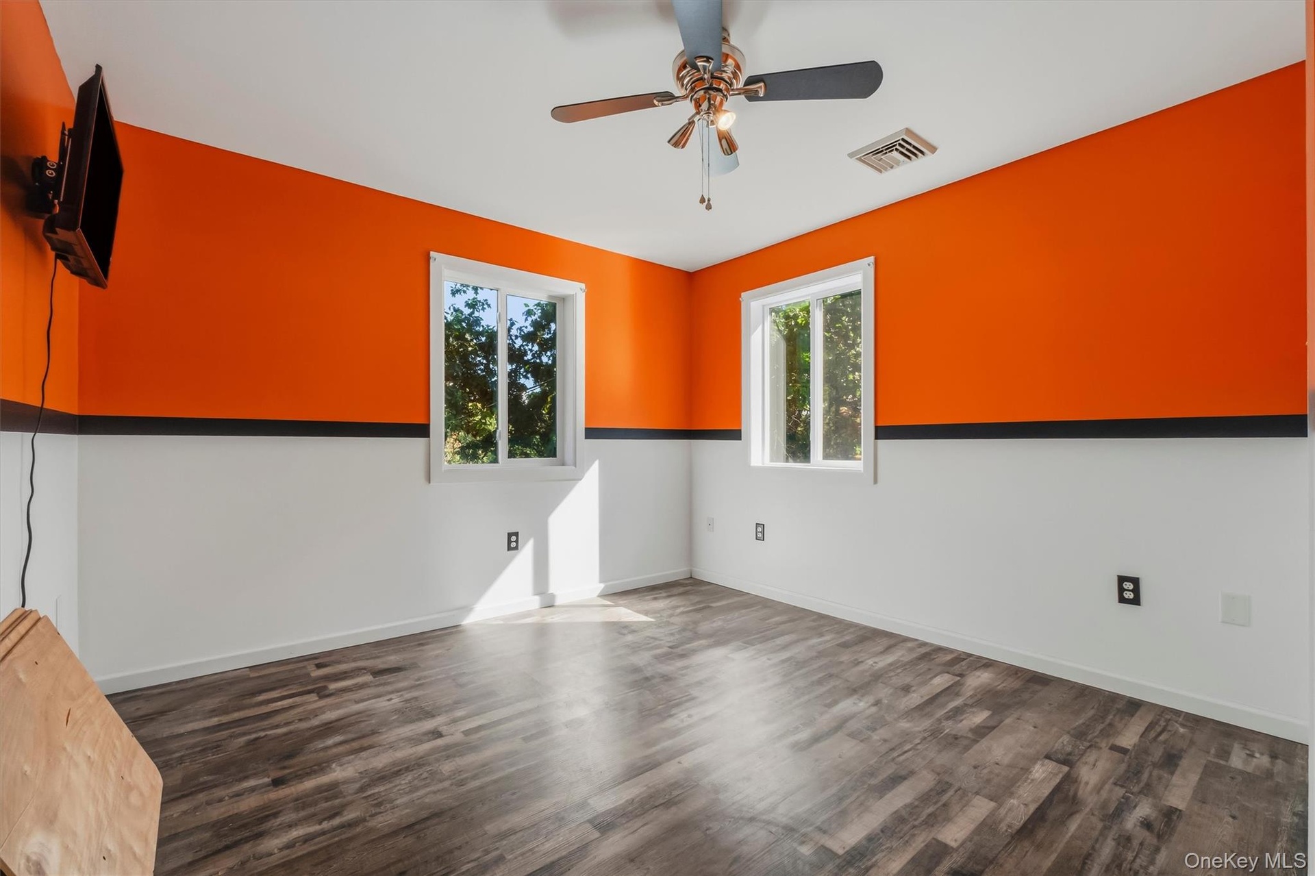 Bedroom 2 with Wood-finish flooring with a two-tone wall design, two windows, and a ceiling fan