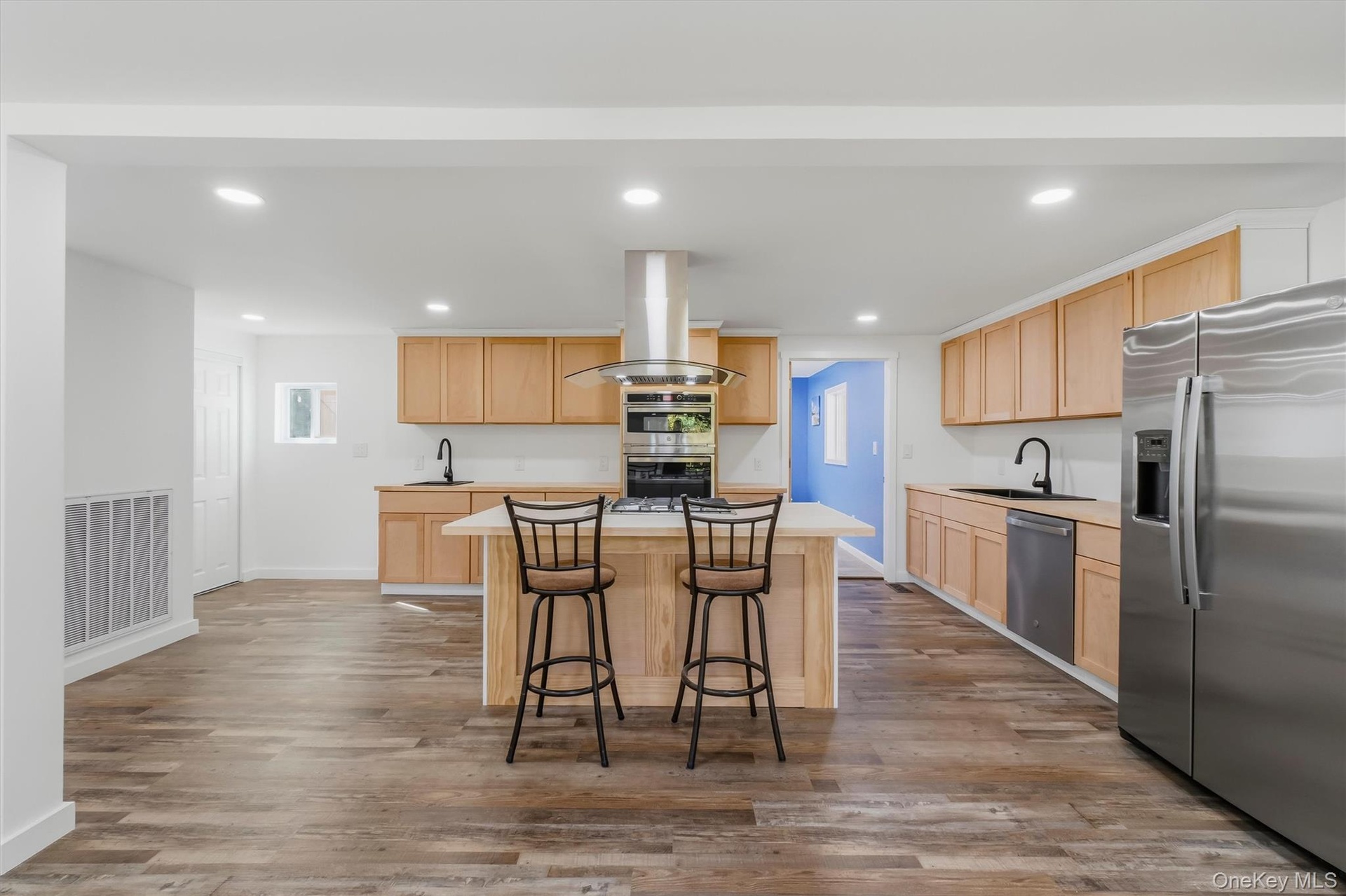 Kitchen featuring wood-finish flooring, recessed lighting, wood cabinetry, a center island, and stainless steel appliances