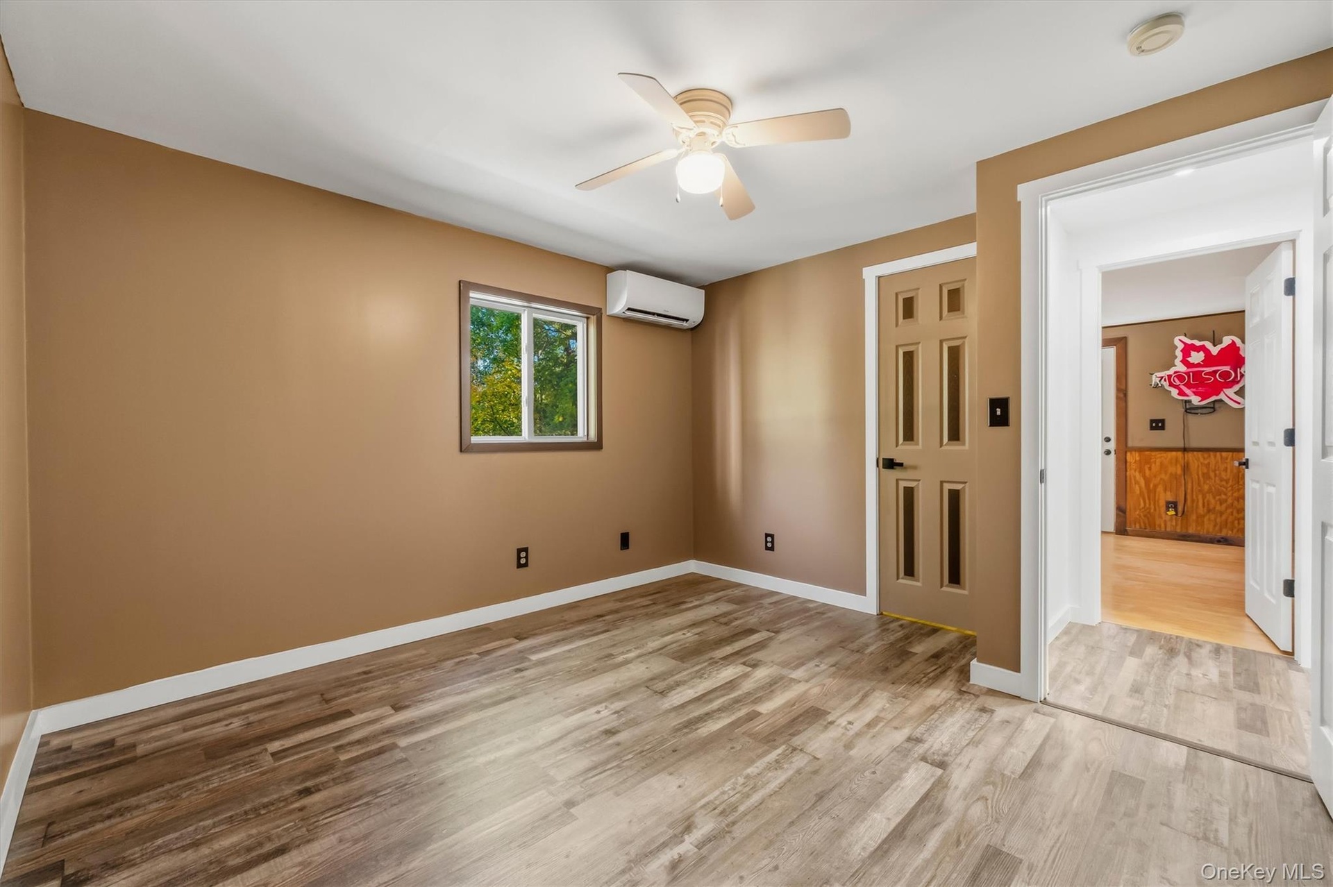 Wood-finish flooring with a ceiling fan, window, and split-system climate control unit